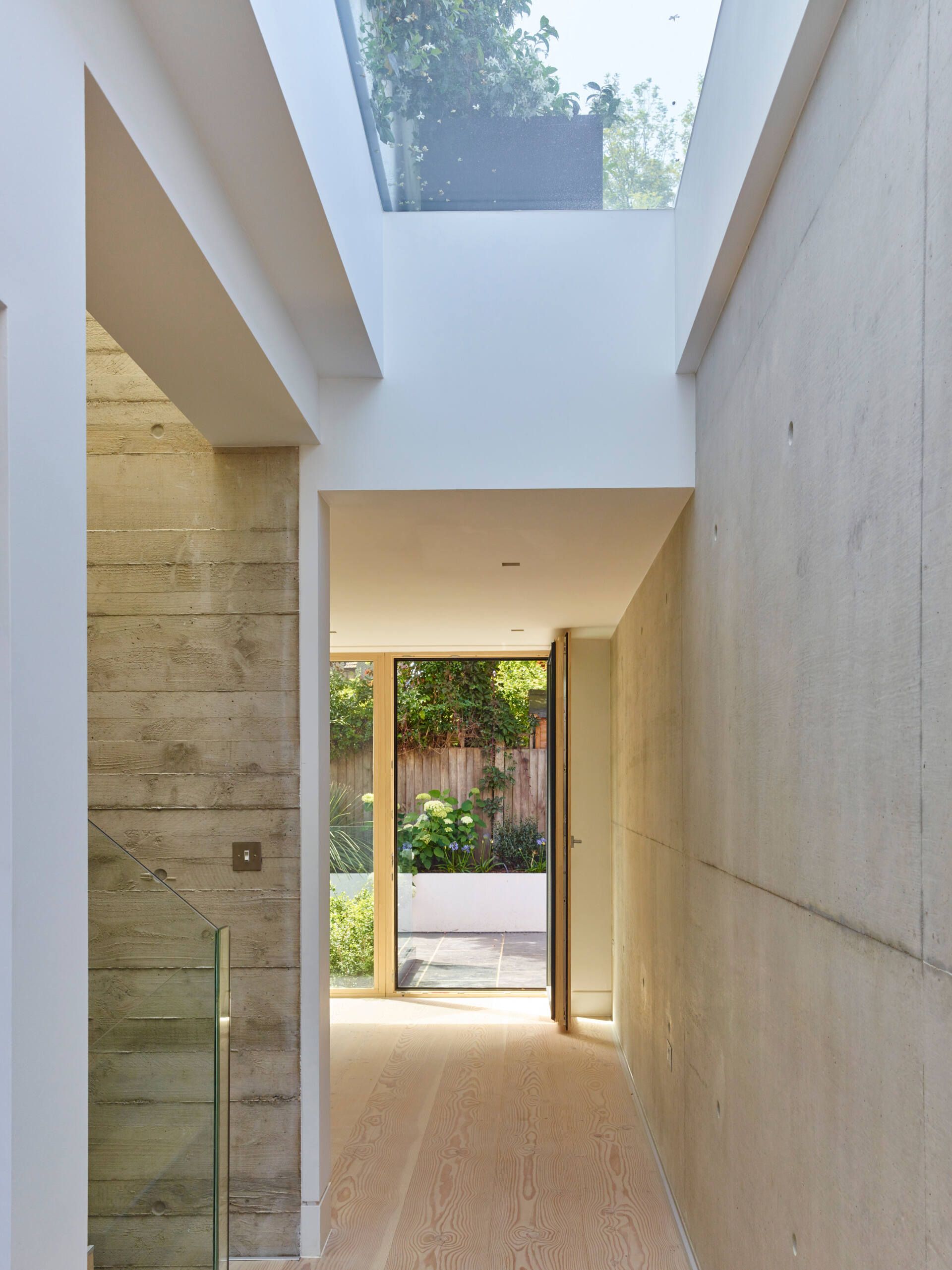Modern narrow hallway with stone walls, skylight, and a view to an outdoor courtyard