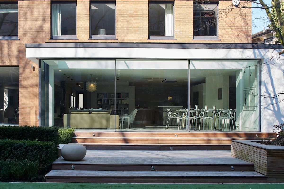 Modern brick building facade with a large glass-walled patio and outdoor seating area