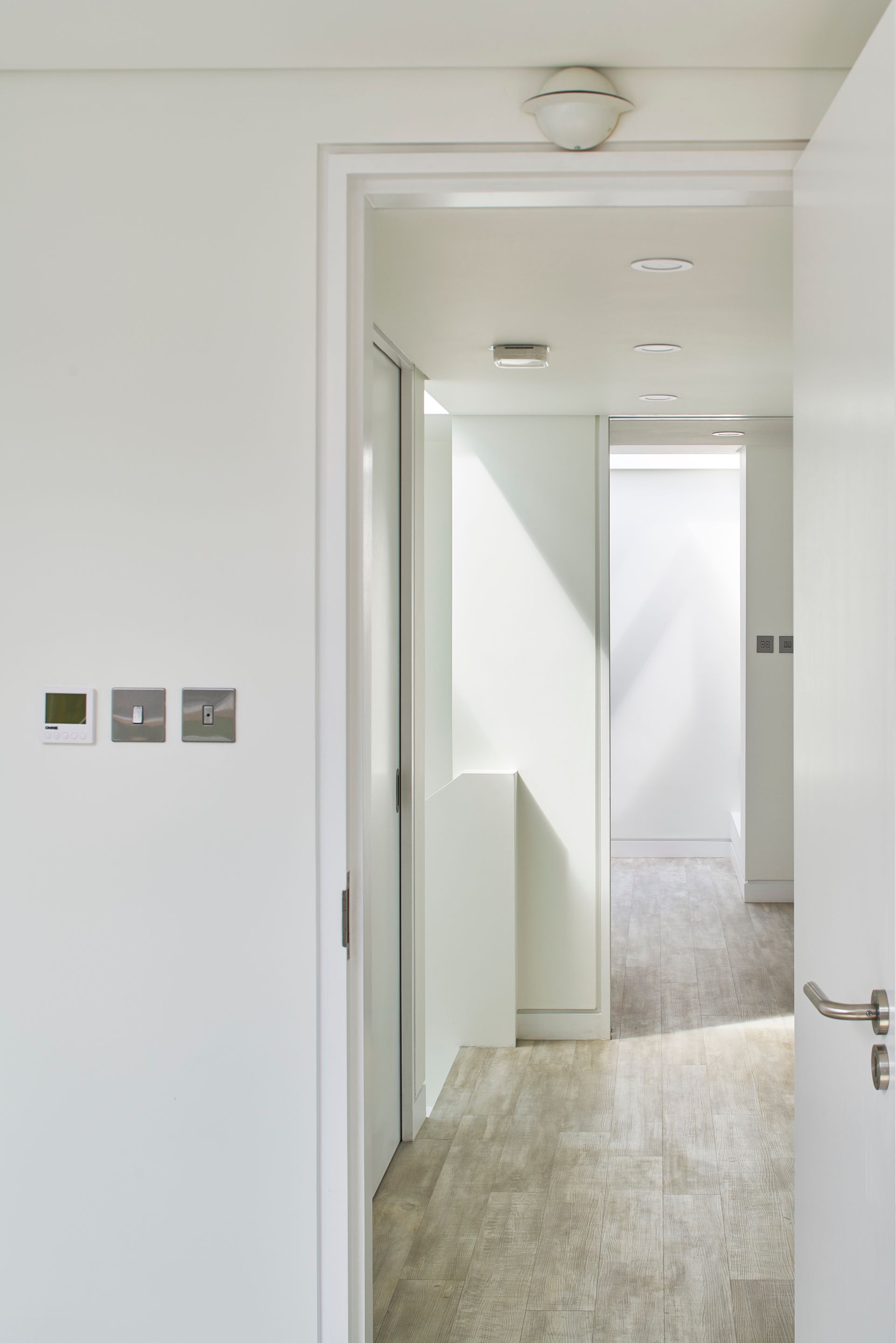Bright hallway with white walls, open doorways, and gray carpet in a modern interior.