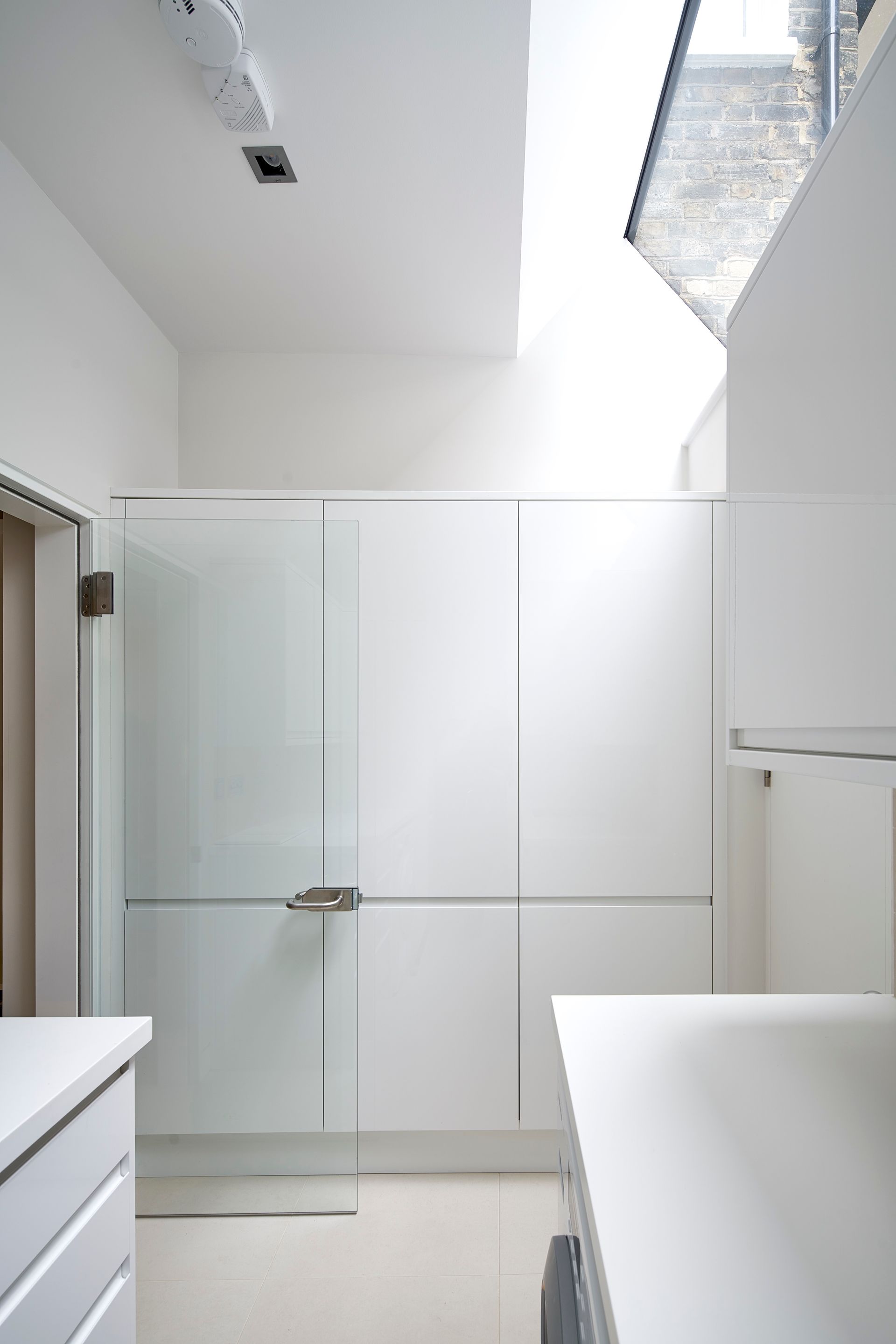Modern white bathroom with glass shower enclosure and skylight, minimalist and bright