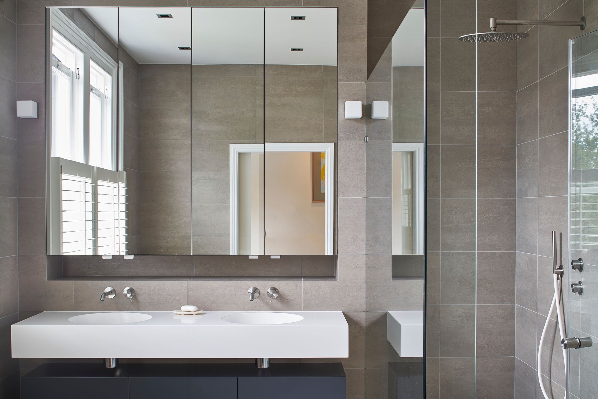 Modern bathroom with double vanity, large mirror, and glass-enclosed shower in neutral tones