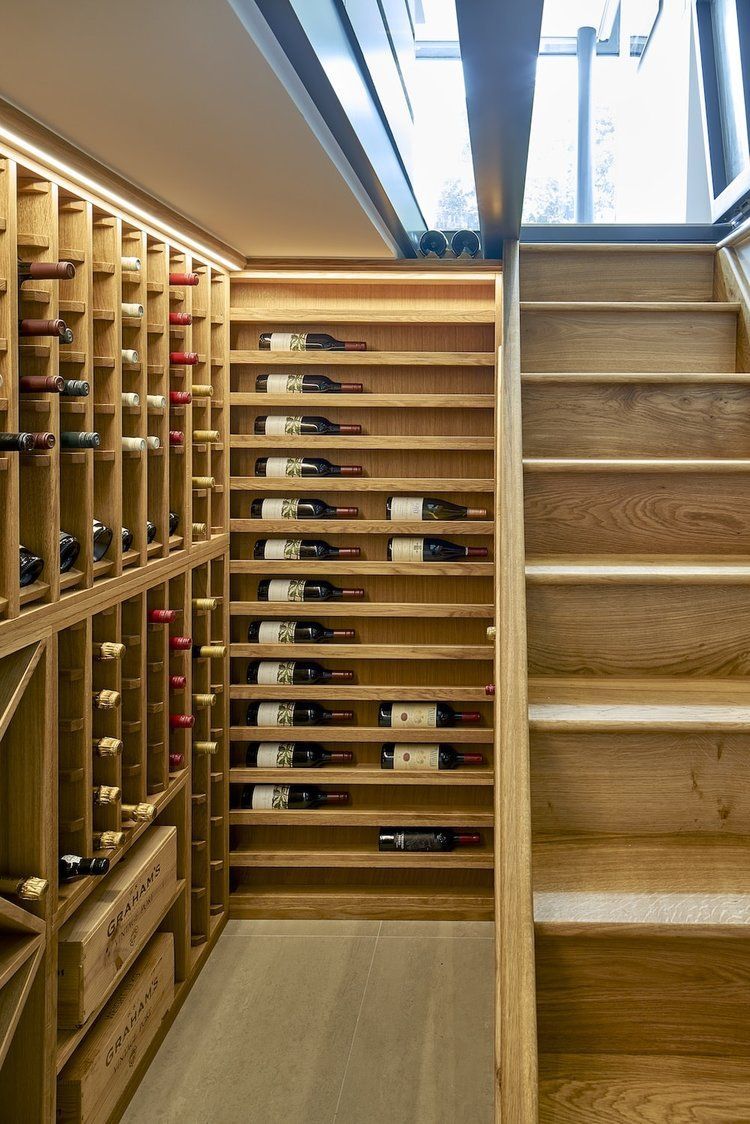 Wooden wine cellar with bottle racks and a narrow staircase beneath a skylight