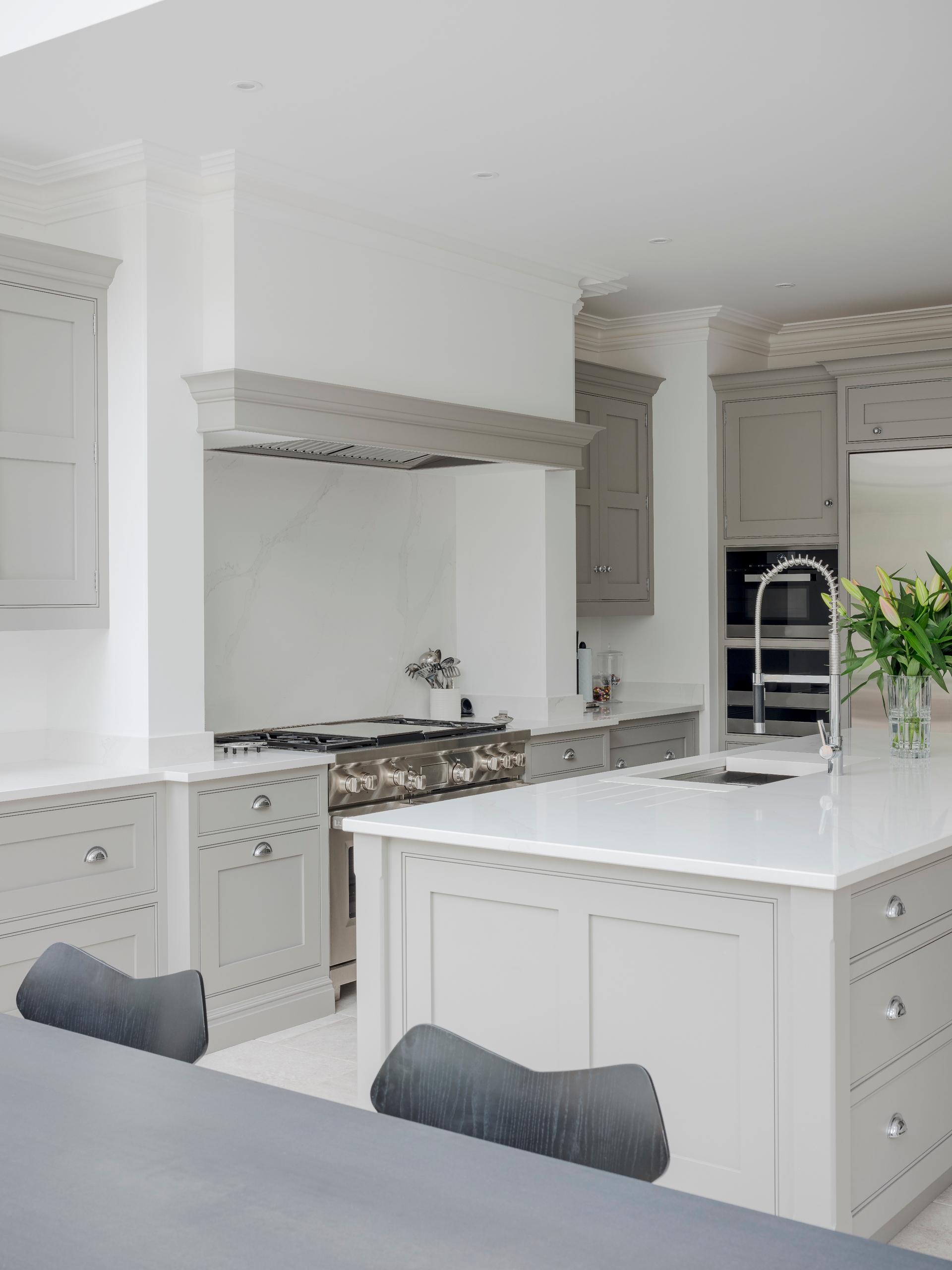 Bright white modern kitchen with island, gray cabinets, and stainless steel range hood