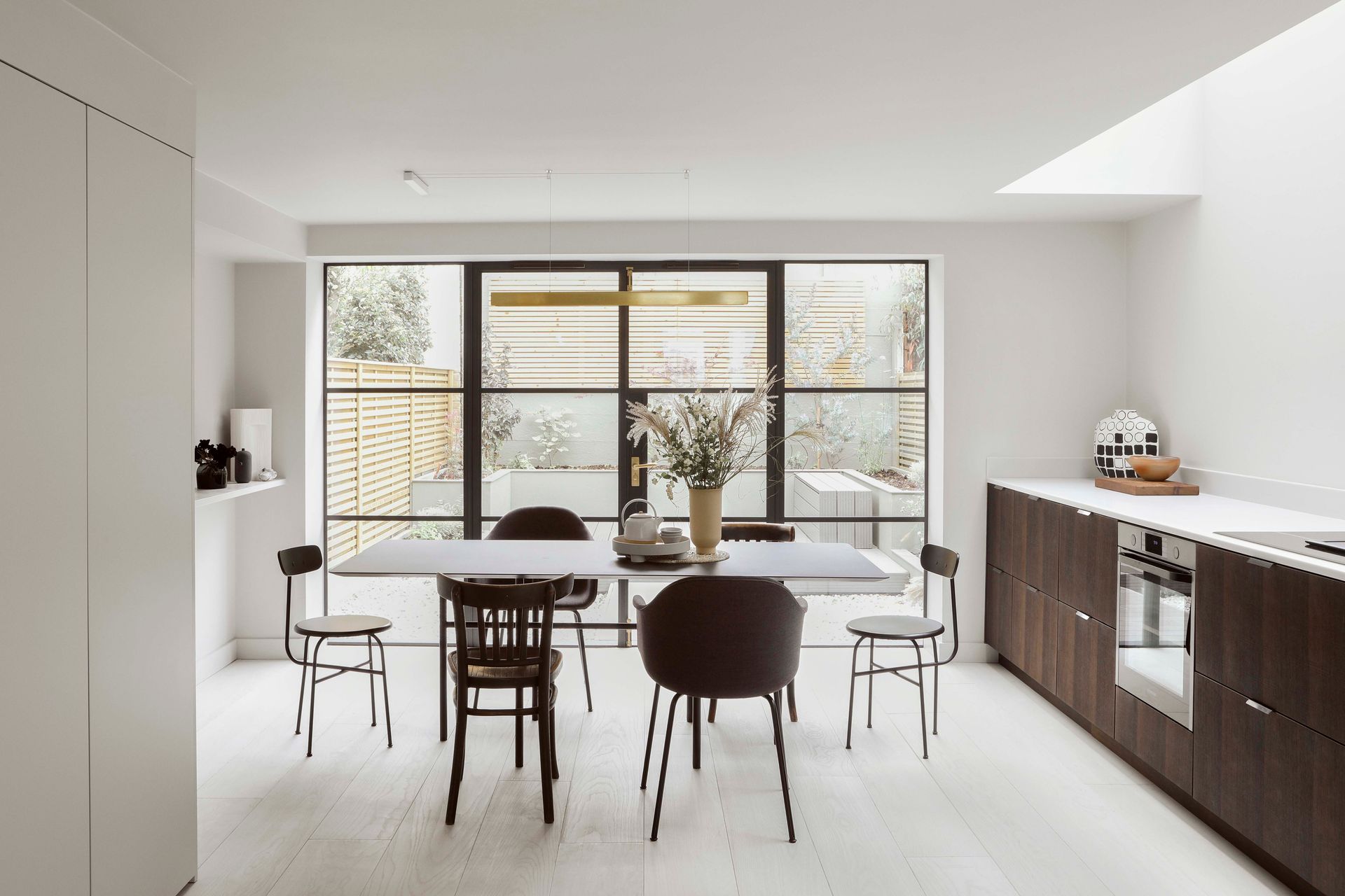 Modern minimalist kitchen with dining table, chairs, and large window light