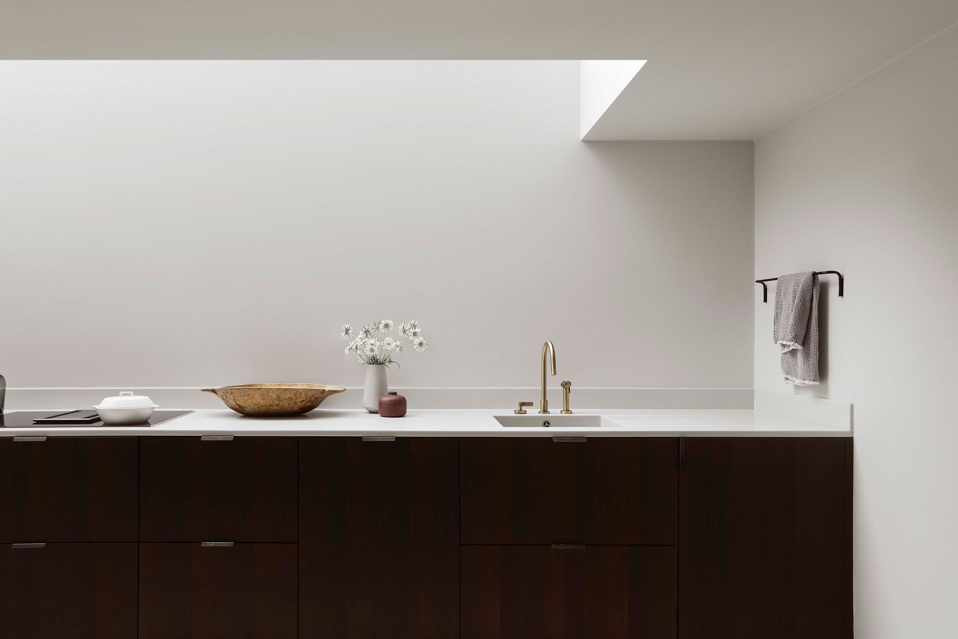 Minimalist kitchen with dark cabinets, white countertop, sink, and small decor items