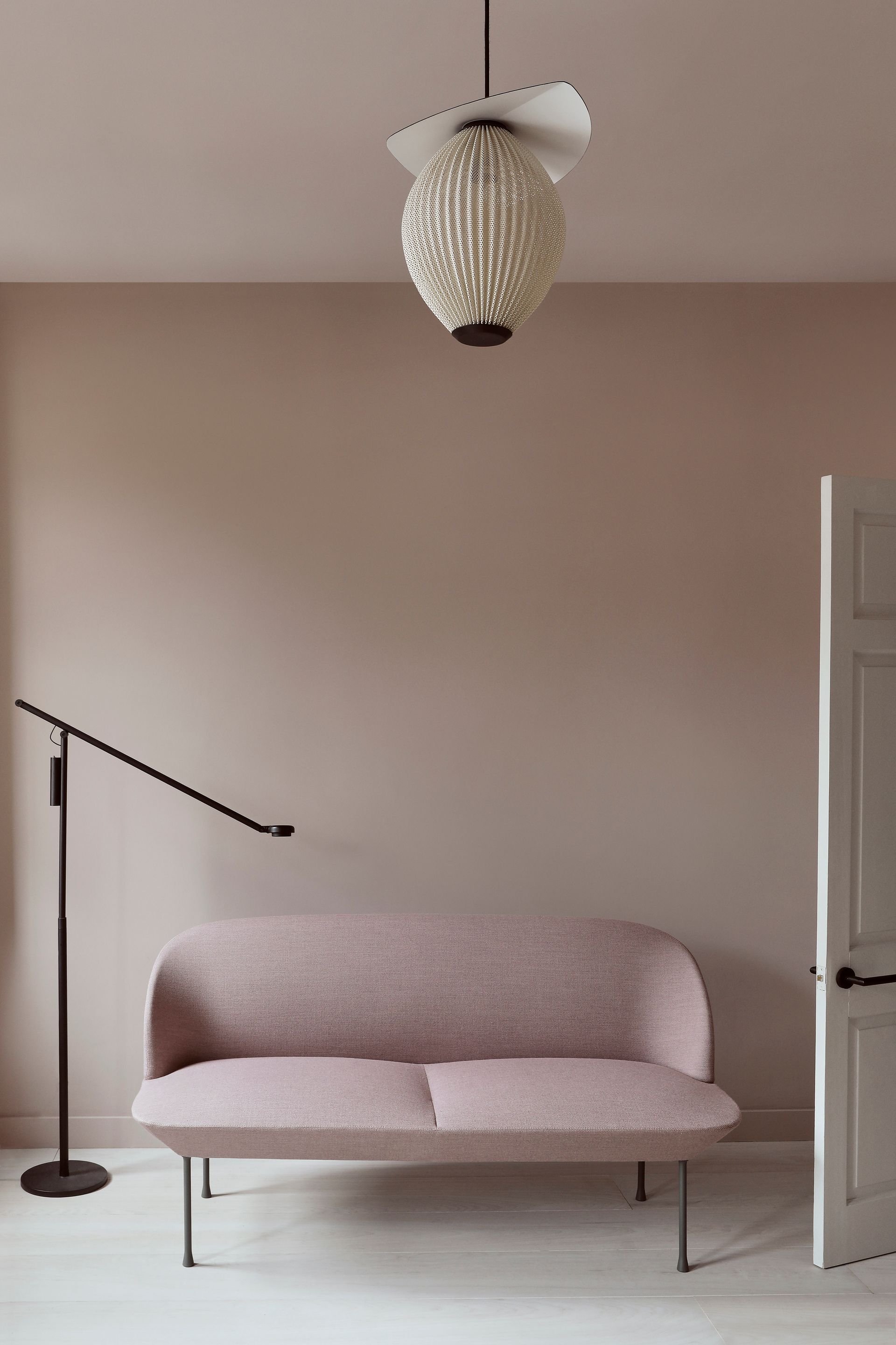 Minimal pink living room with sofa, floor lamp, and hanging light fixture