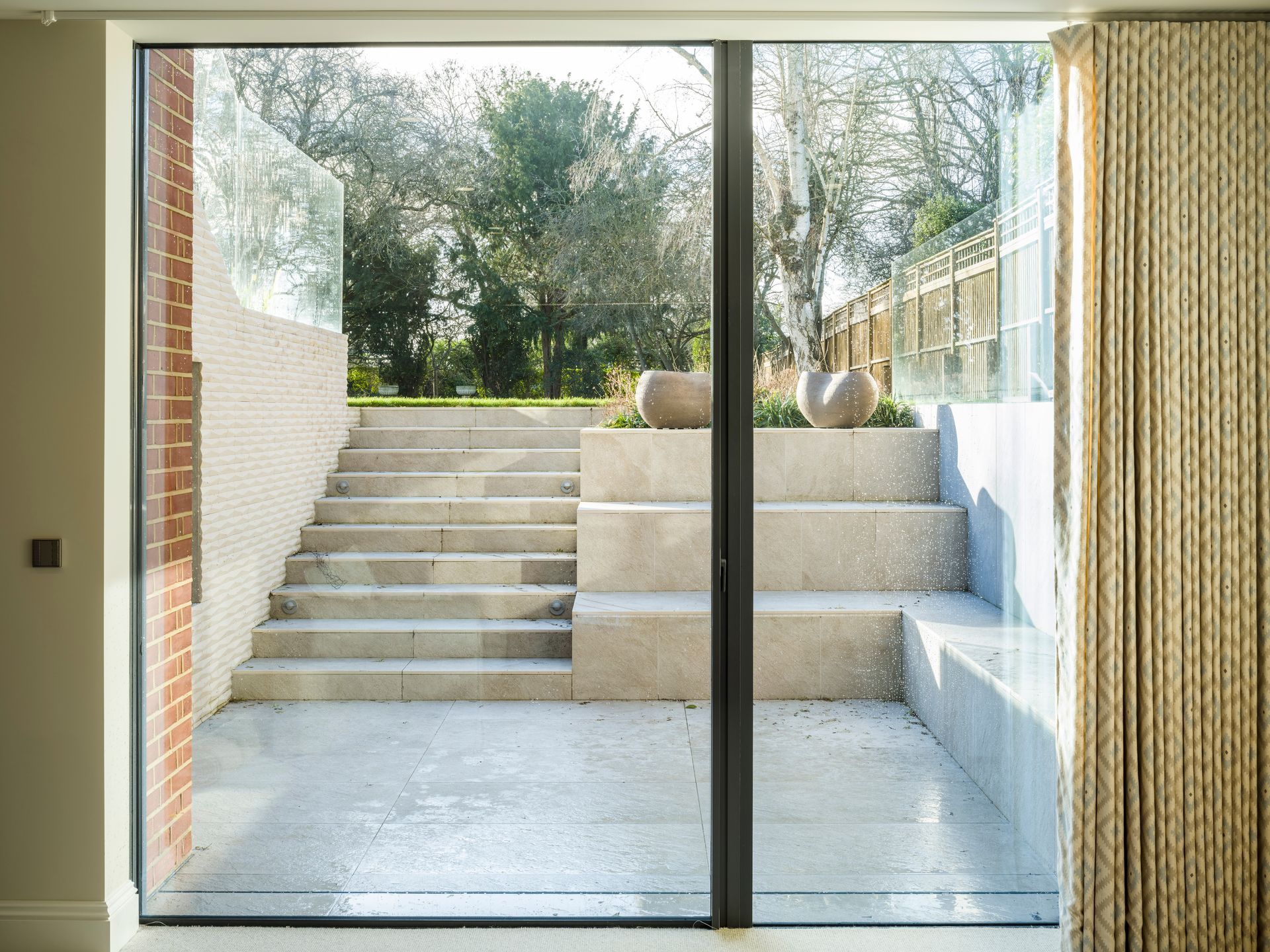 Sliding glass doors opening to a stepped outdoor patio with trees beyond.