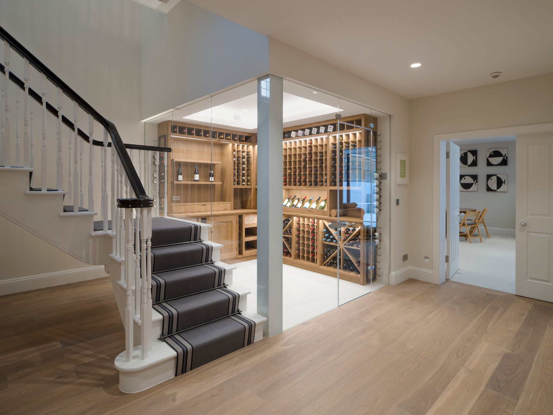 Bright basement stairway beside a wine cellar with wooden racks and an open doorway