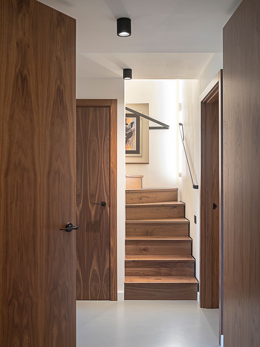 Wood-paneled hallway with stairs leading up to a bright landing and framed artwork.