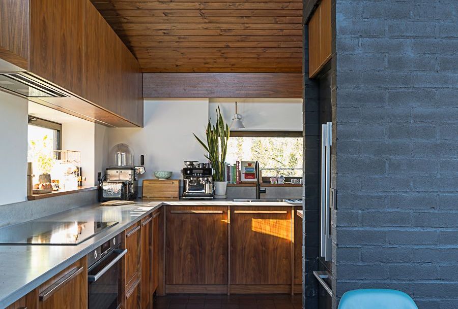 Wooden kitchen with countertop, cabinets, and appliances; view of a window.