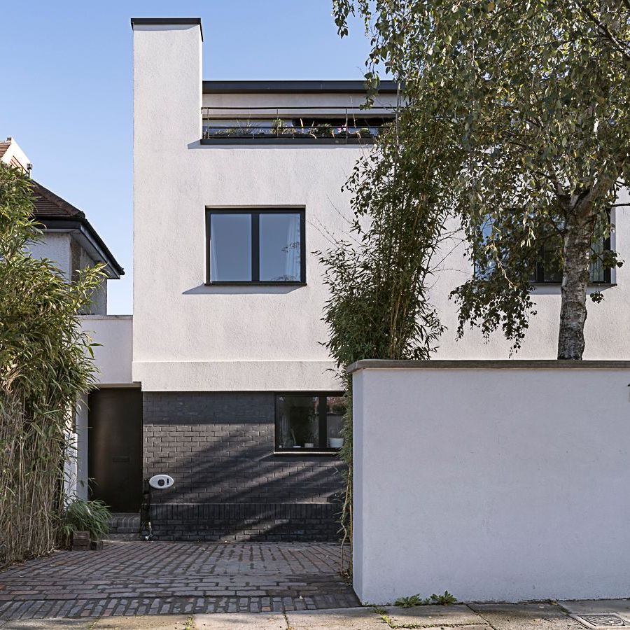 Modern white two-story house with a garage, front gate, and tree-lined street view
