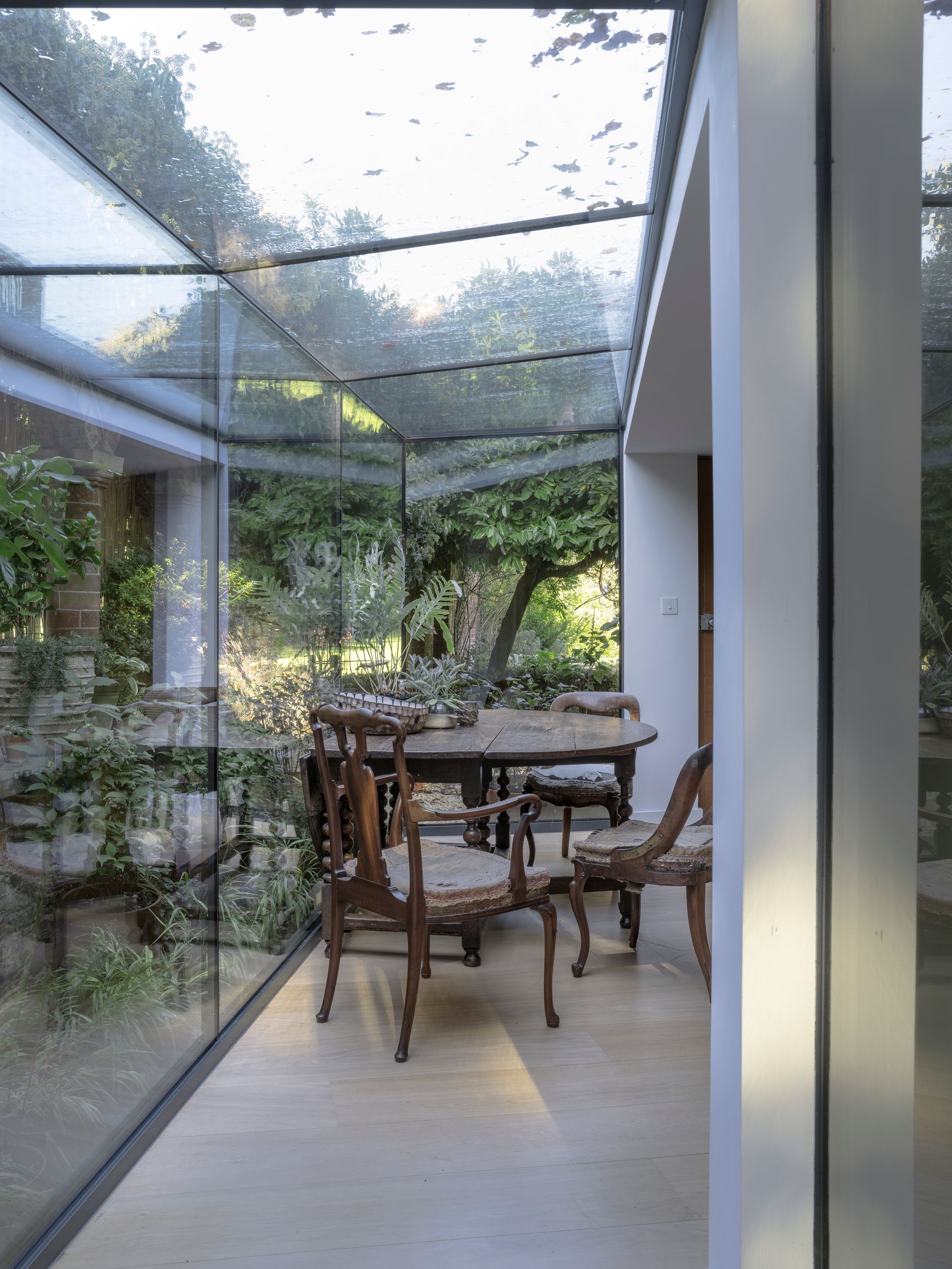 Covered patio dining area with wooden table and chairs beside a garden walkway