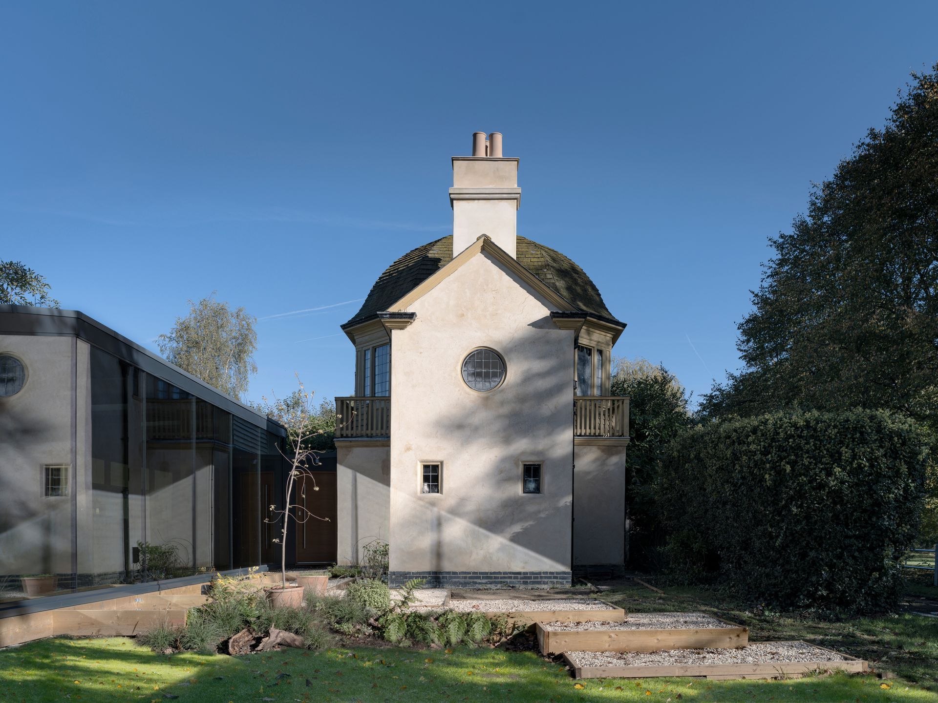 White, domed-roof building with circular window, next to a modern structure under a blue sky.