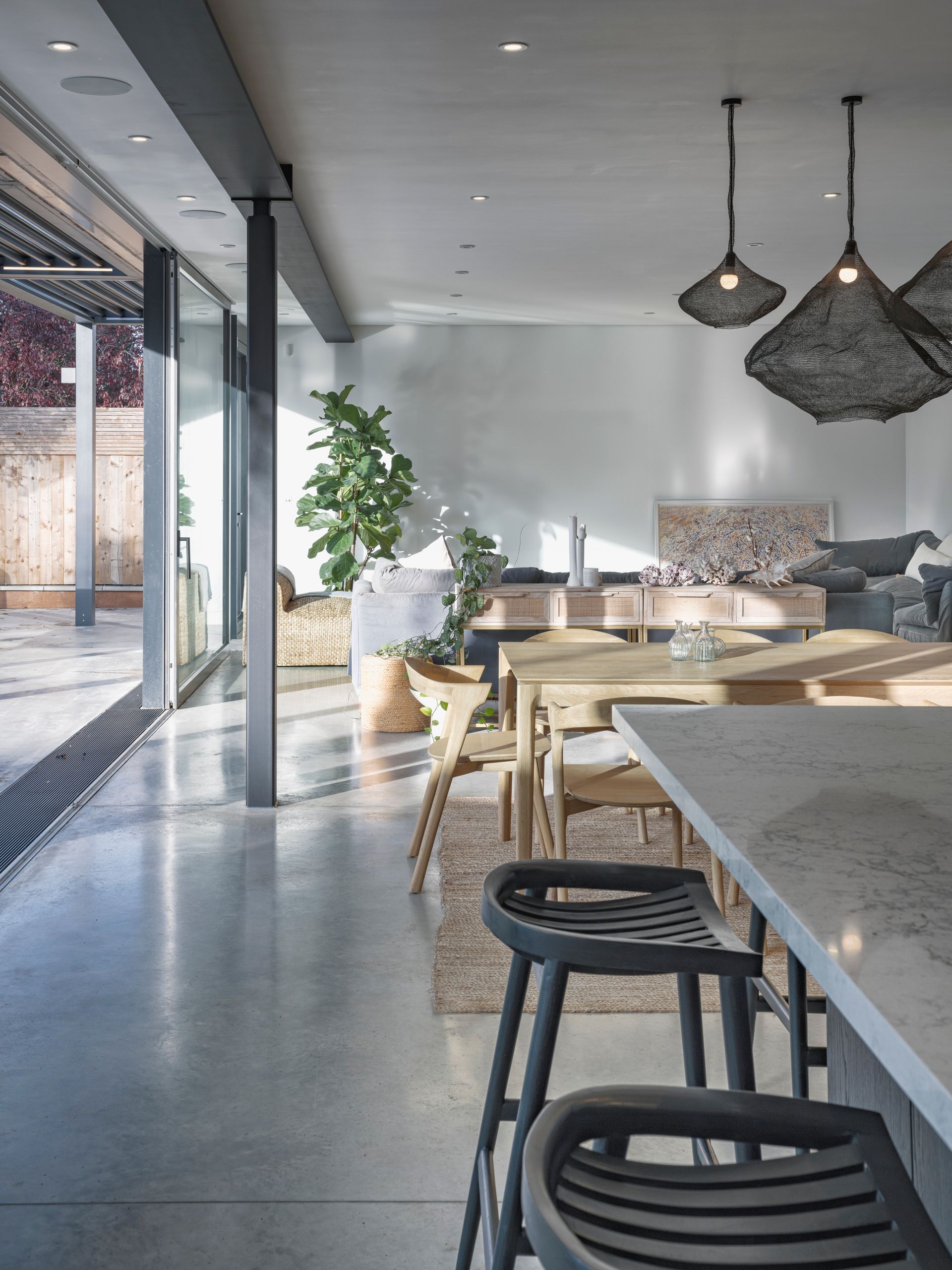Modern cafe interior with large windows, stone tables, wooden chairs, and hanging pendant lights