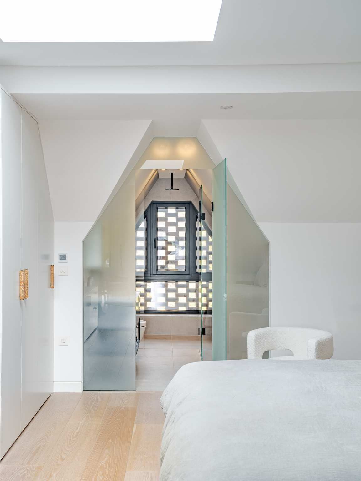 Bright minimalist bedroom with open glass doors leading to a tiled bathroom or hallway at the back