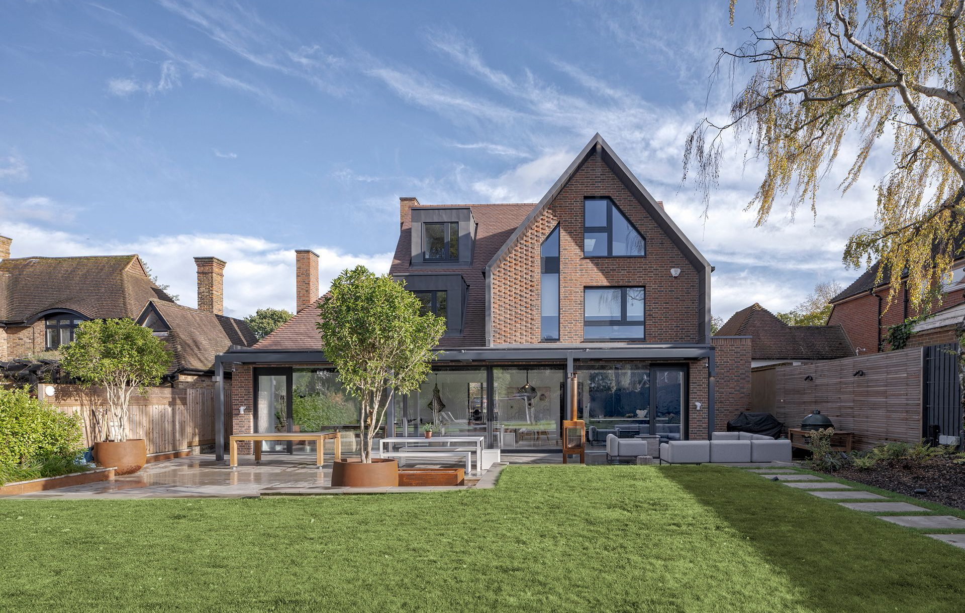 Modern house with glass doors and a large green lawn under a blue sky