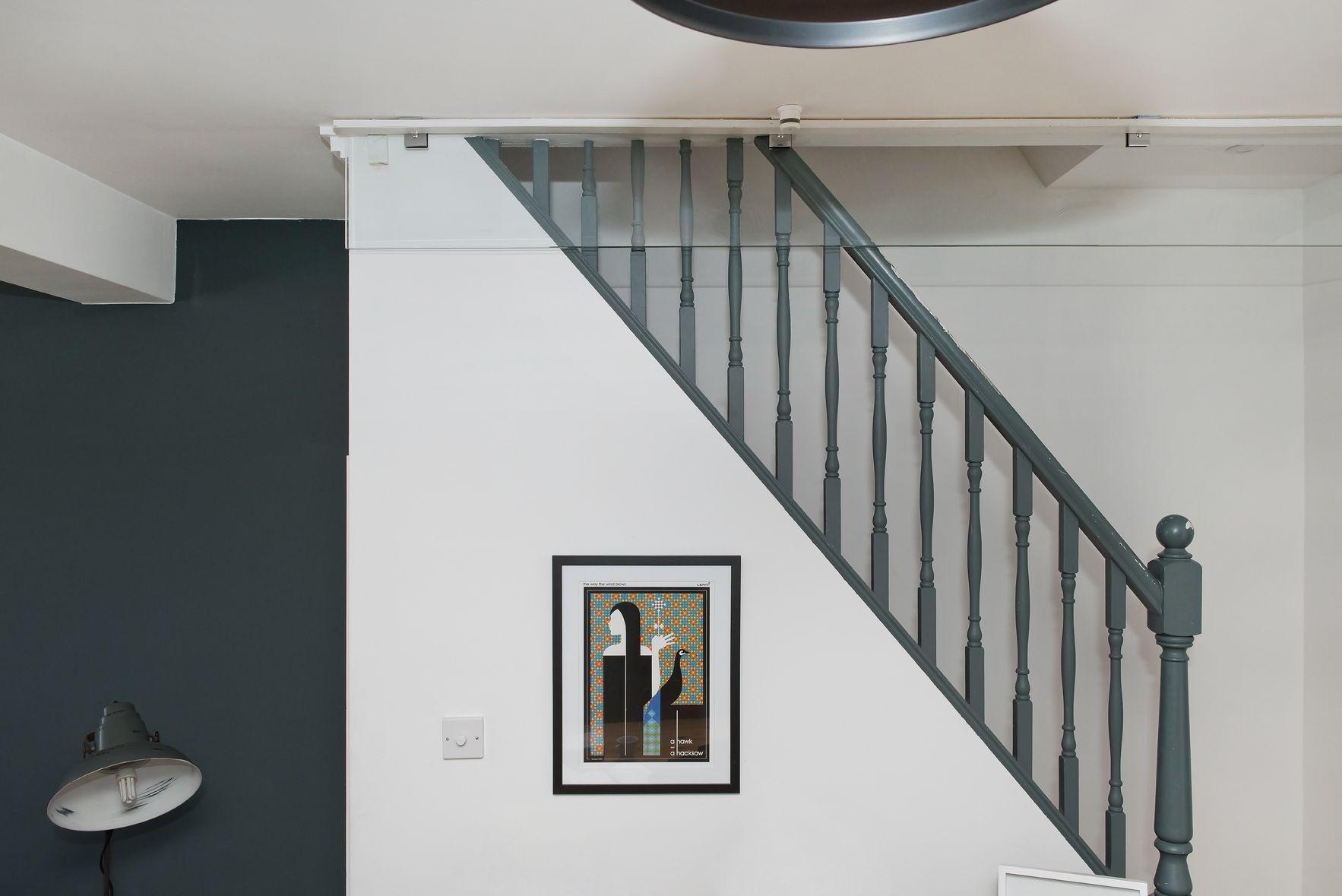Indoor stairway with gray railings, white walls, and a framed picture on the wall.