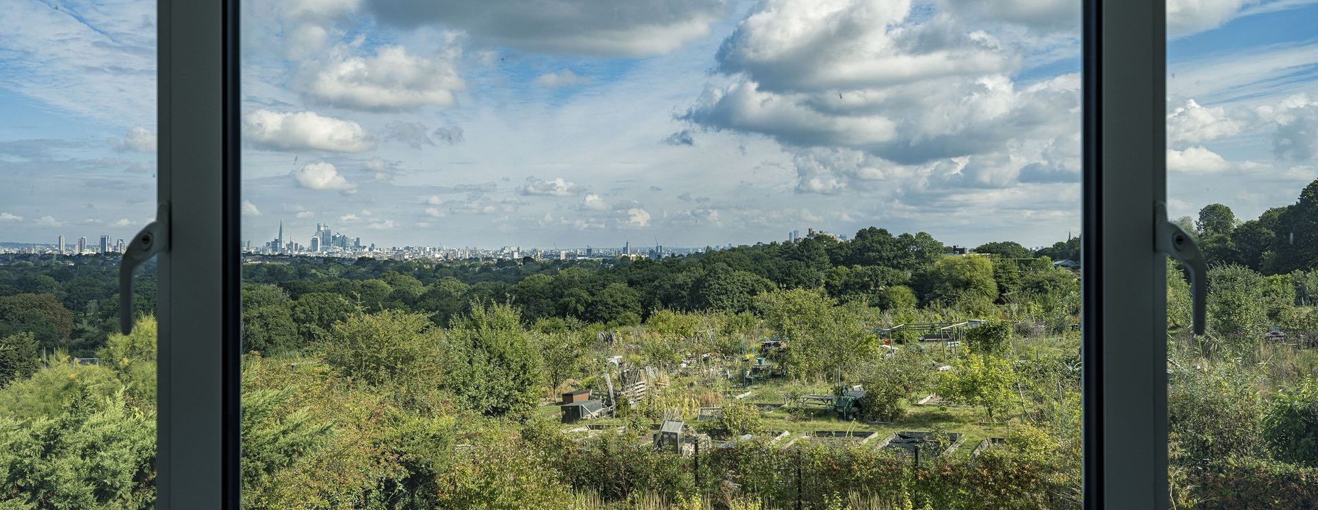 View through a window of a lush green landscape under a cloudy sky