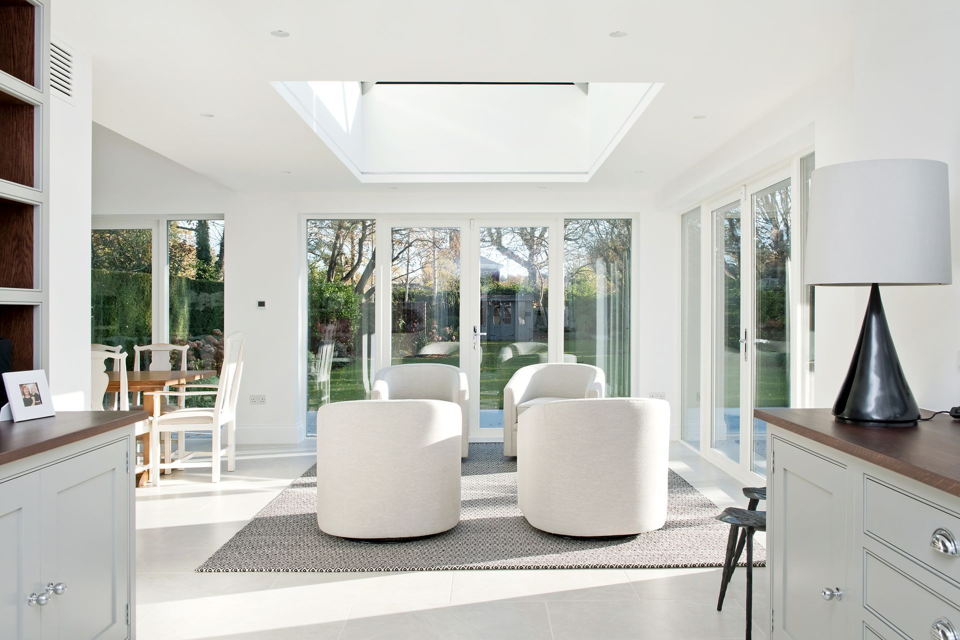 Bright white living room with two chairs, skylight, and large windows overlooking a garden
