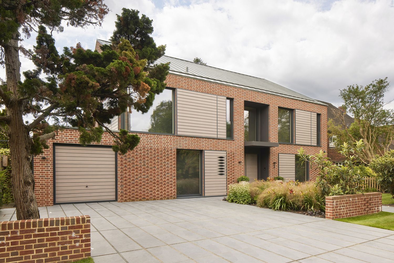 Modern two-story house with brick and wood exterior, driveway, and landscaped front yard