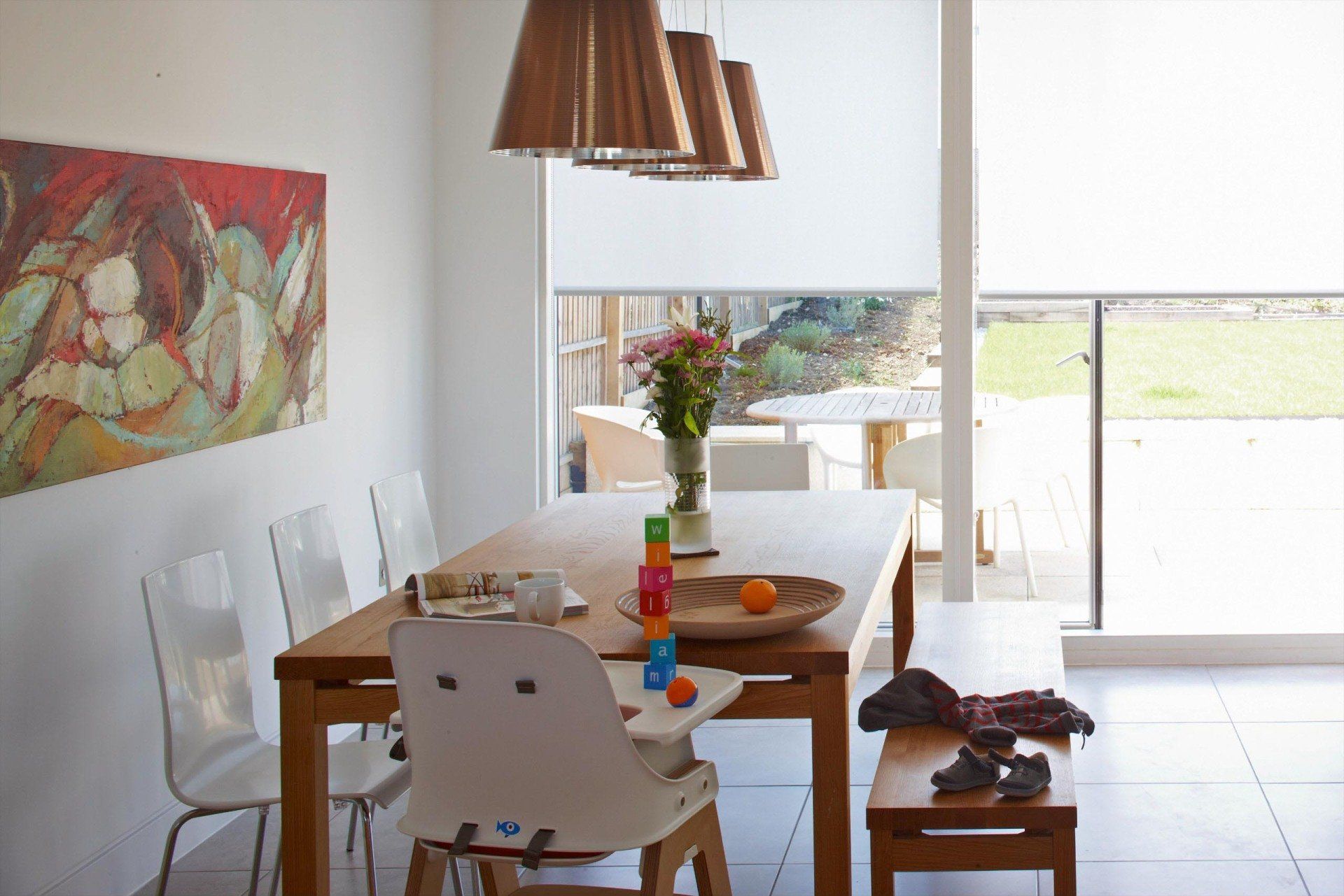Bright dining room with wooden table, white chairs, wall art, and sliding glass doors to a patio.