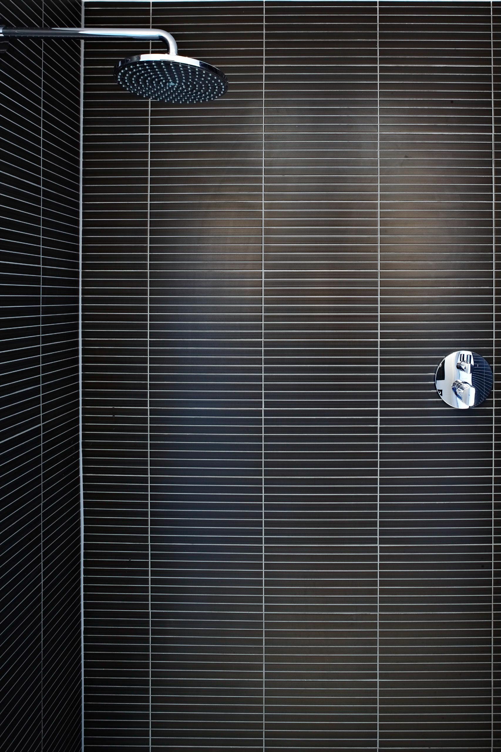 Close-up of dark window blinds with a silver blind pull on the right and a black cord at the top left
