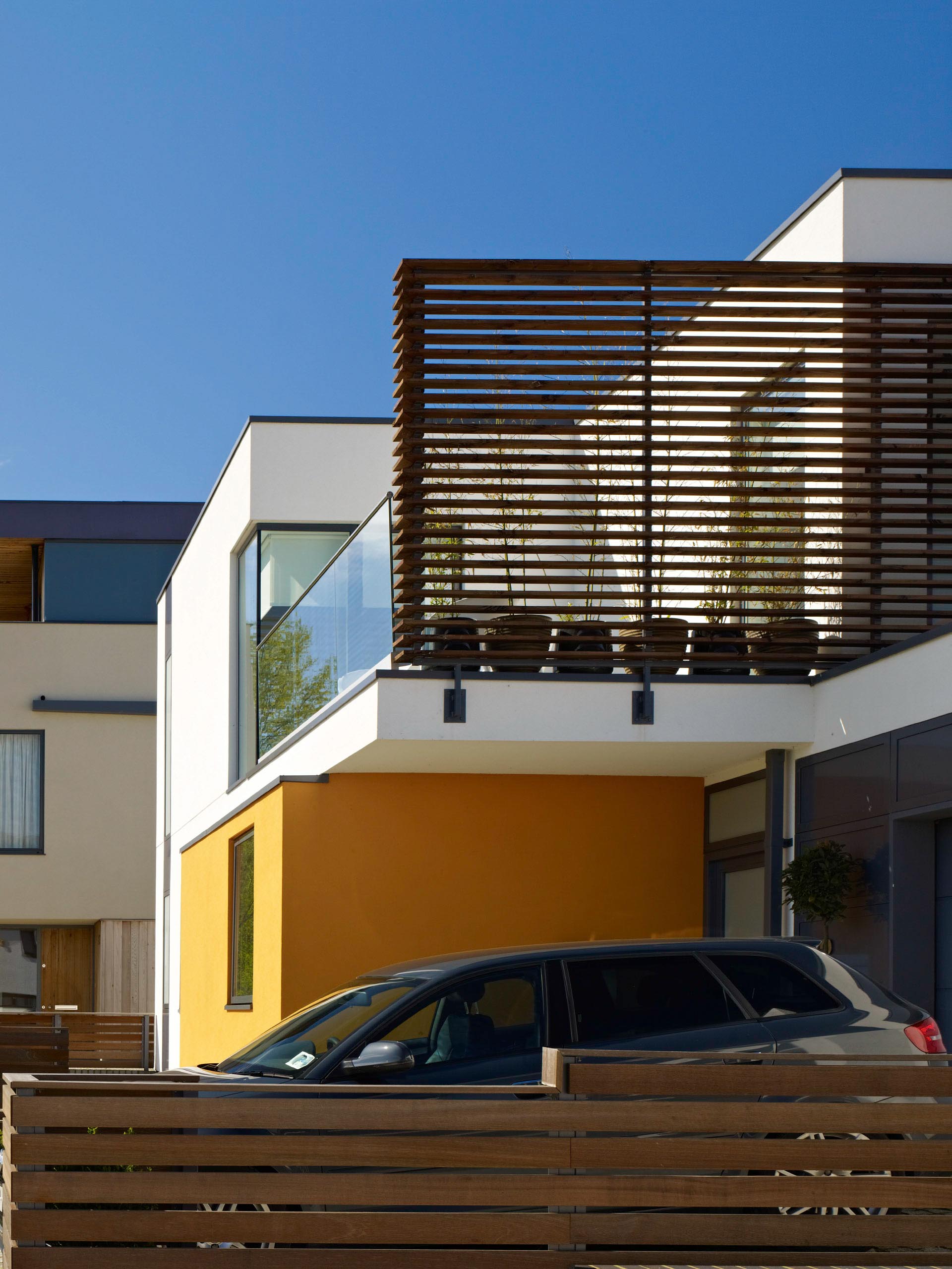 Modern house exterior with wood slat balcony and a parked car in front