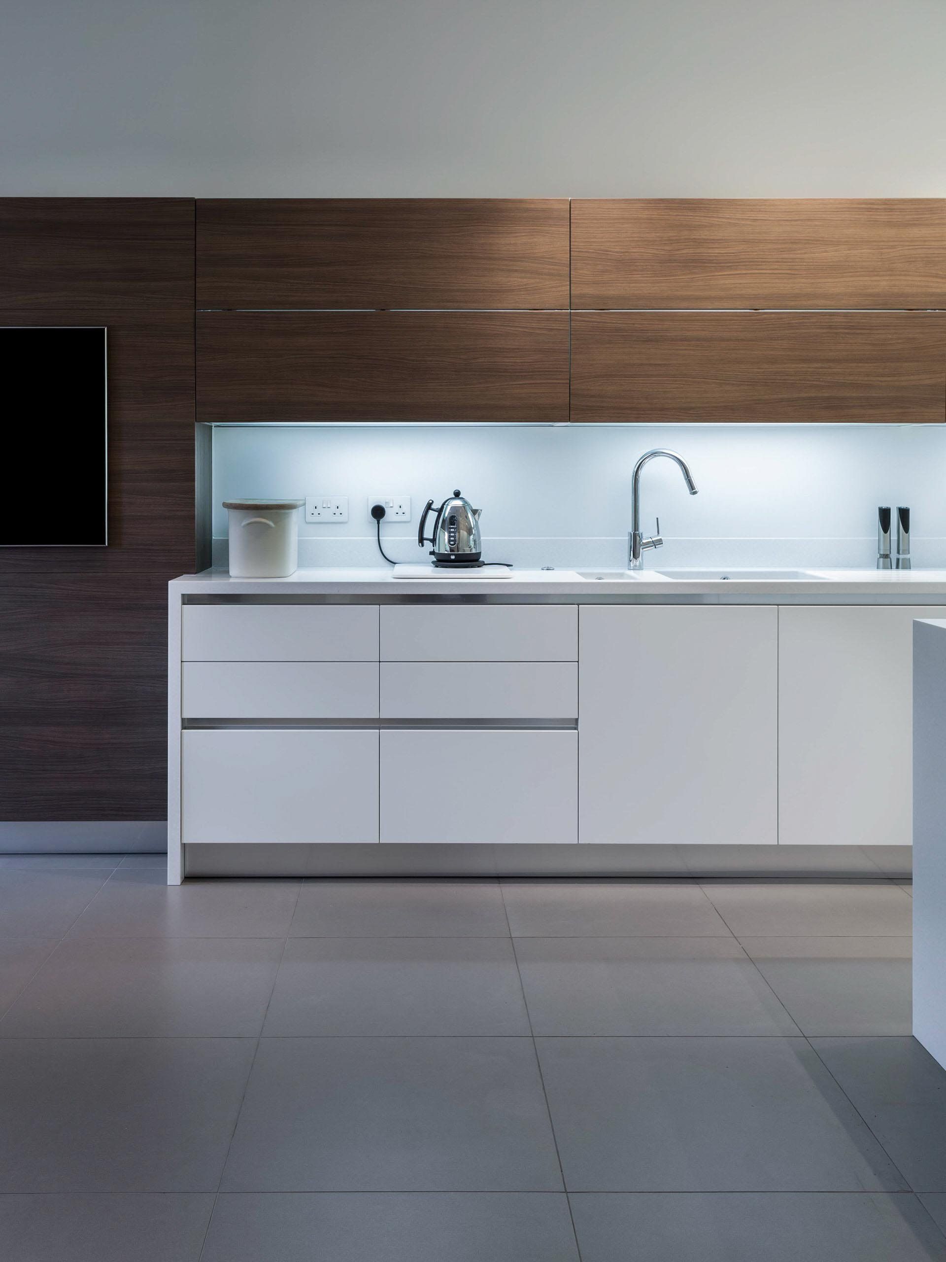 Modern kitchen with white cabinets, wooden wall panels, sink, and grey tile floor