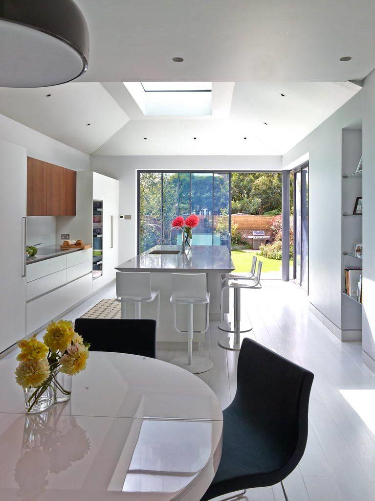 Modern kitchen with white cabinets, island, and large glass doors leading to a backyard.