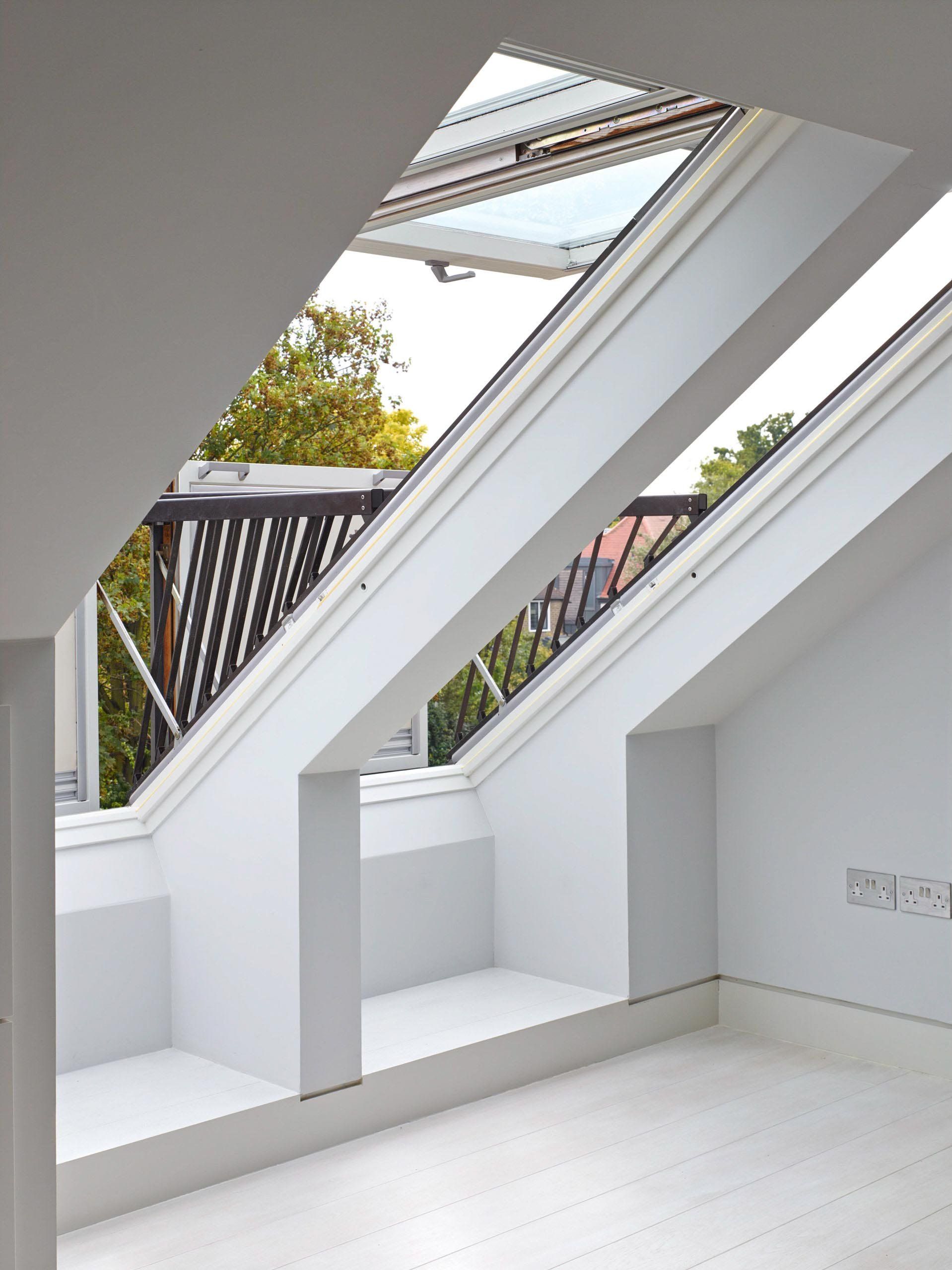 White room with angled skylights overlooking a balcony. One window is open.