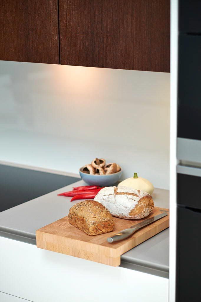Kitchen countertop with bread, knife, peppers, and bowl of mushrooms.