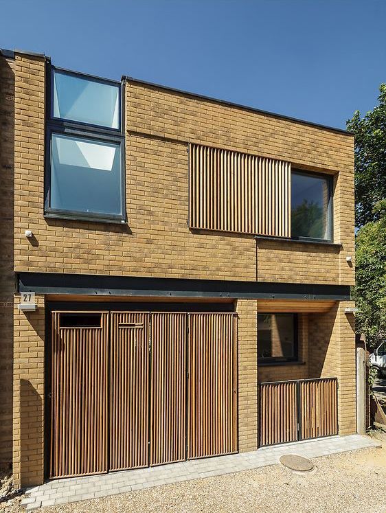 Modern two-story brick house with vertical wooden slats, dark-framed windows, and a small front entrance.