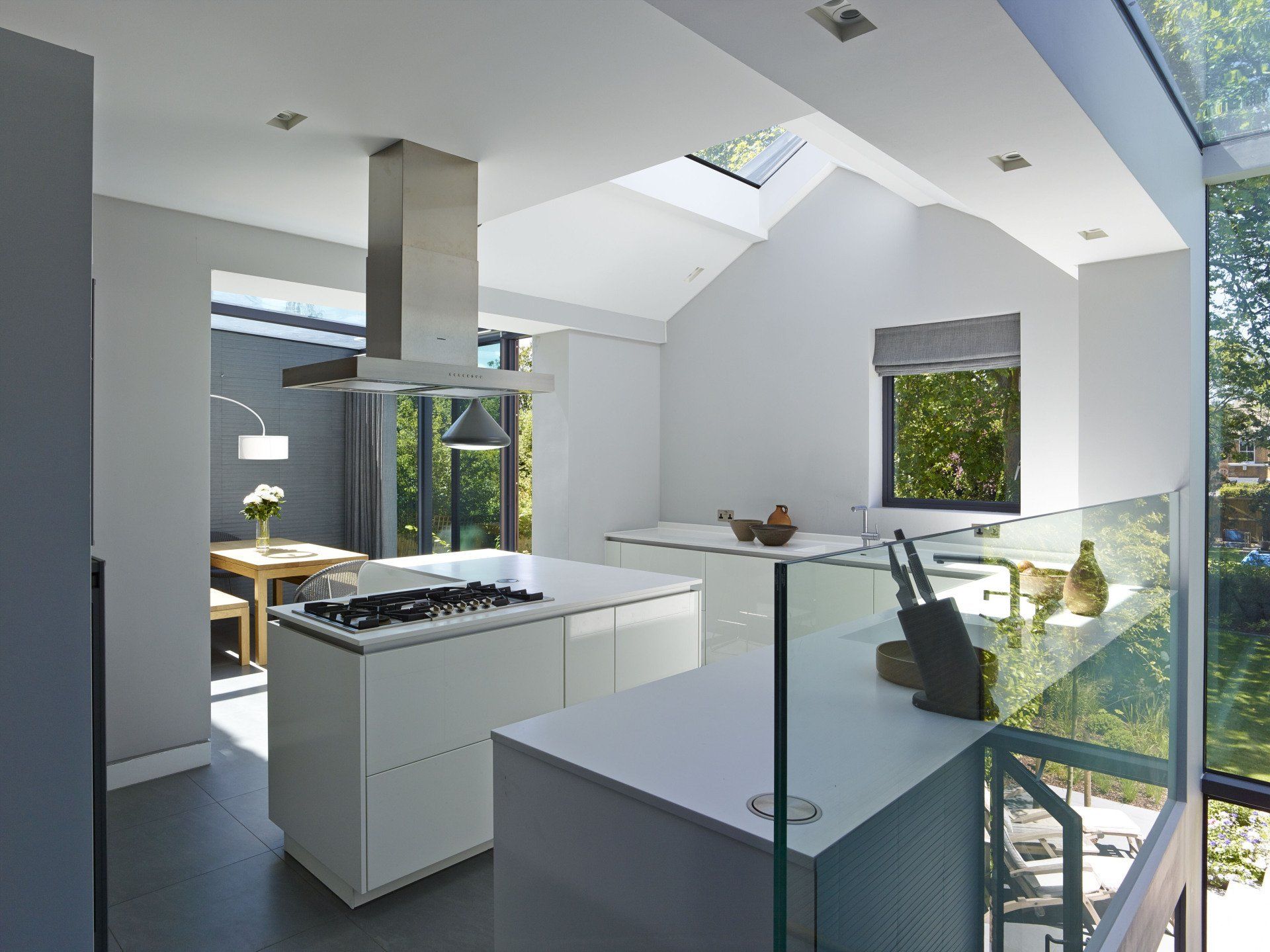 Modern staircase with black vertical railings, white walls, and a small indoor planter below.