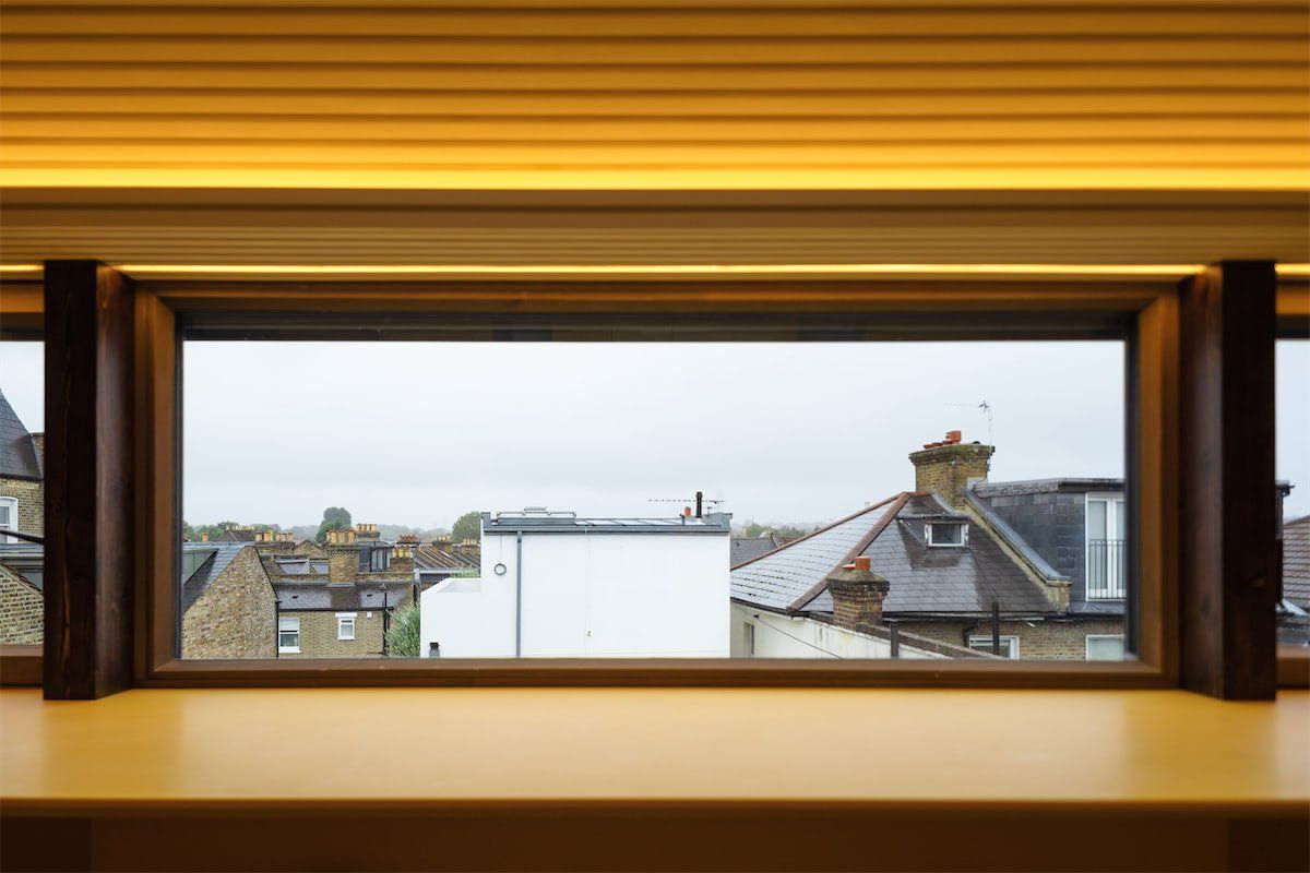 View through a window to rooftops and chimneys under an overcast sky
