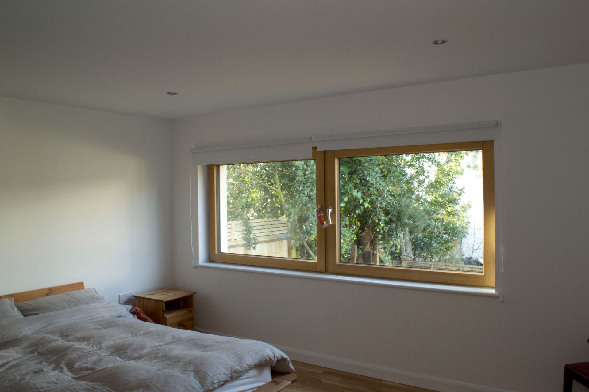 Minimal bedroom with an unmade bed and a large window overlooking trees
