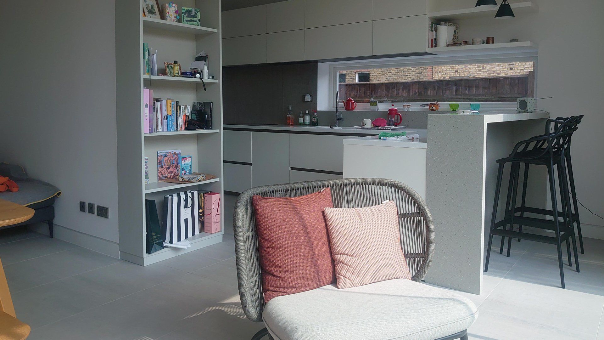 Modern kitchen and living area with white cabinets, bookshelves, and a striped chair in the foreground