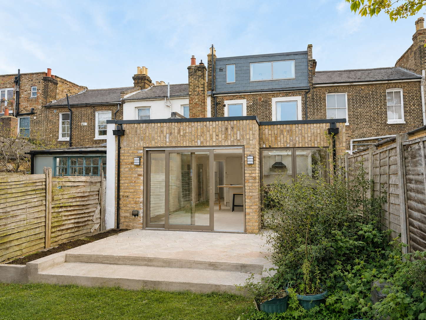 Backyard patio with glass doors and a brick house in the background