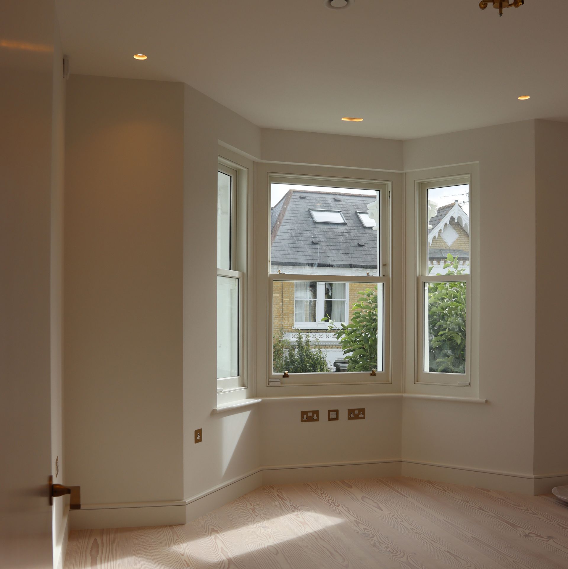 Bright minimalist bedroom with open glass doors leading to a tiled bathroom or hallway at the back