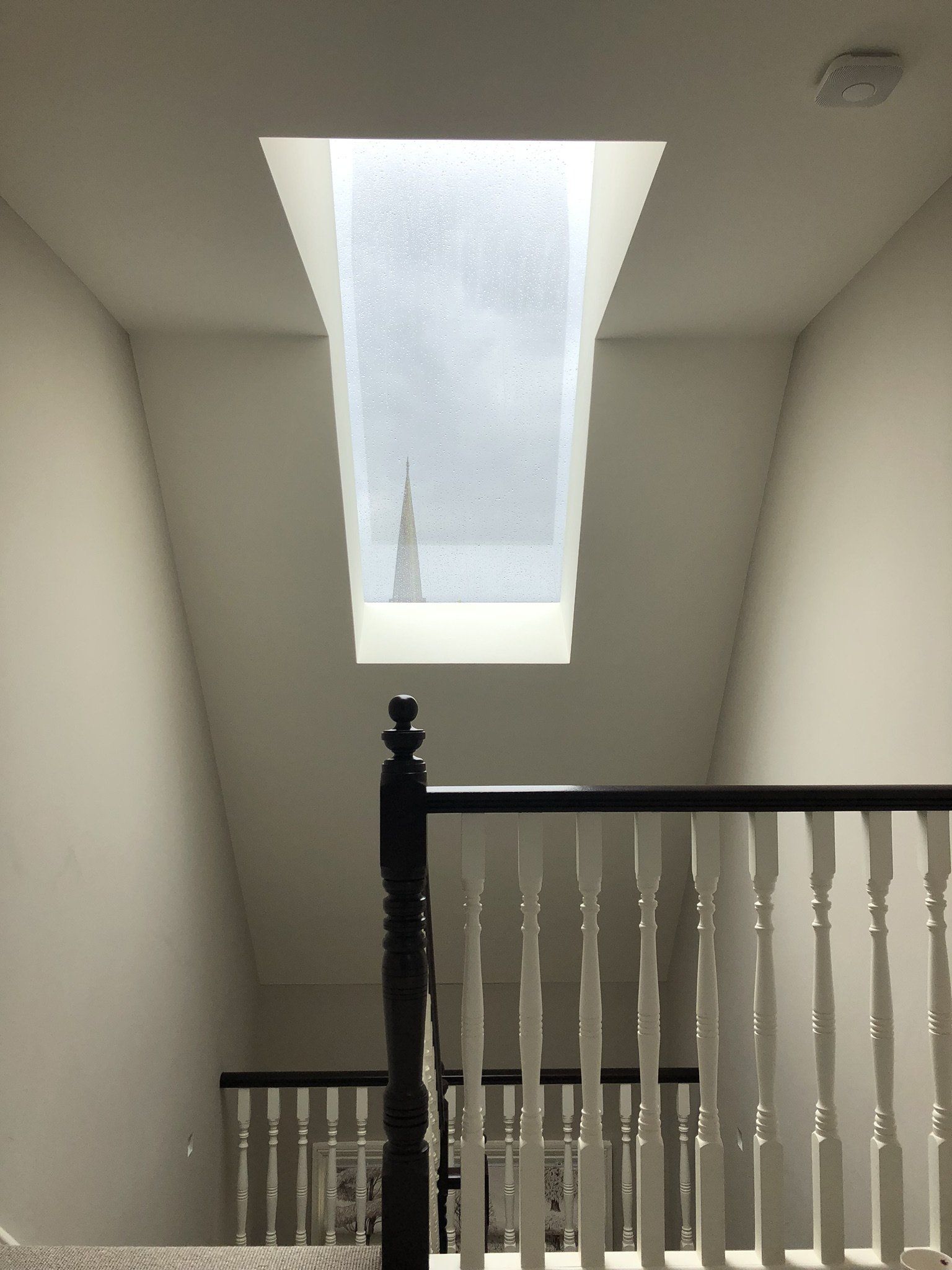 Stairwell with a skylight above and white railings, lit by natural light.