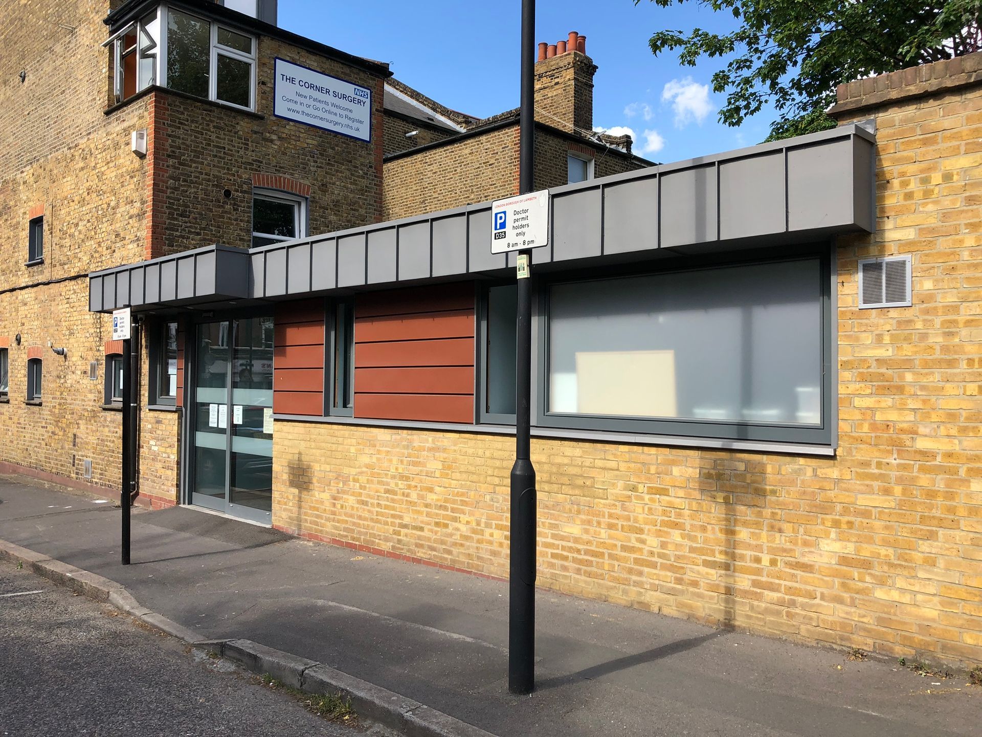 Brick storefront on a quiet street with large windows and a black lamppost out front