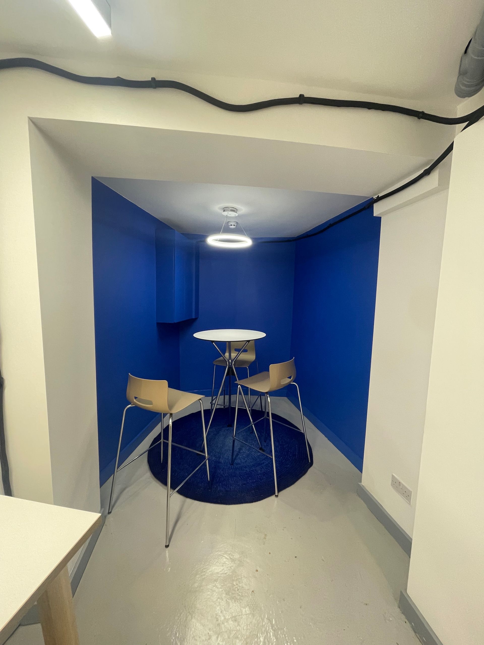 Blue-walled alcove with a small drum kit on a gray floor, viewed through a doorway.
