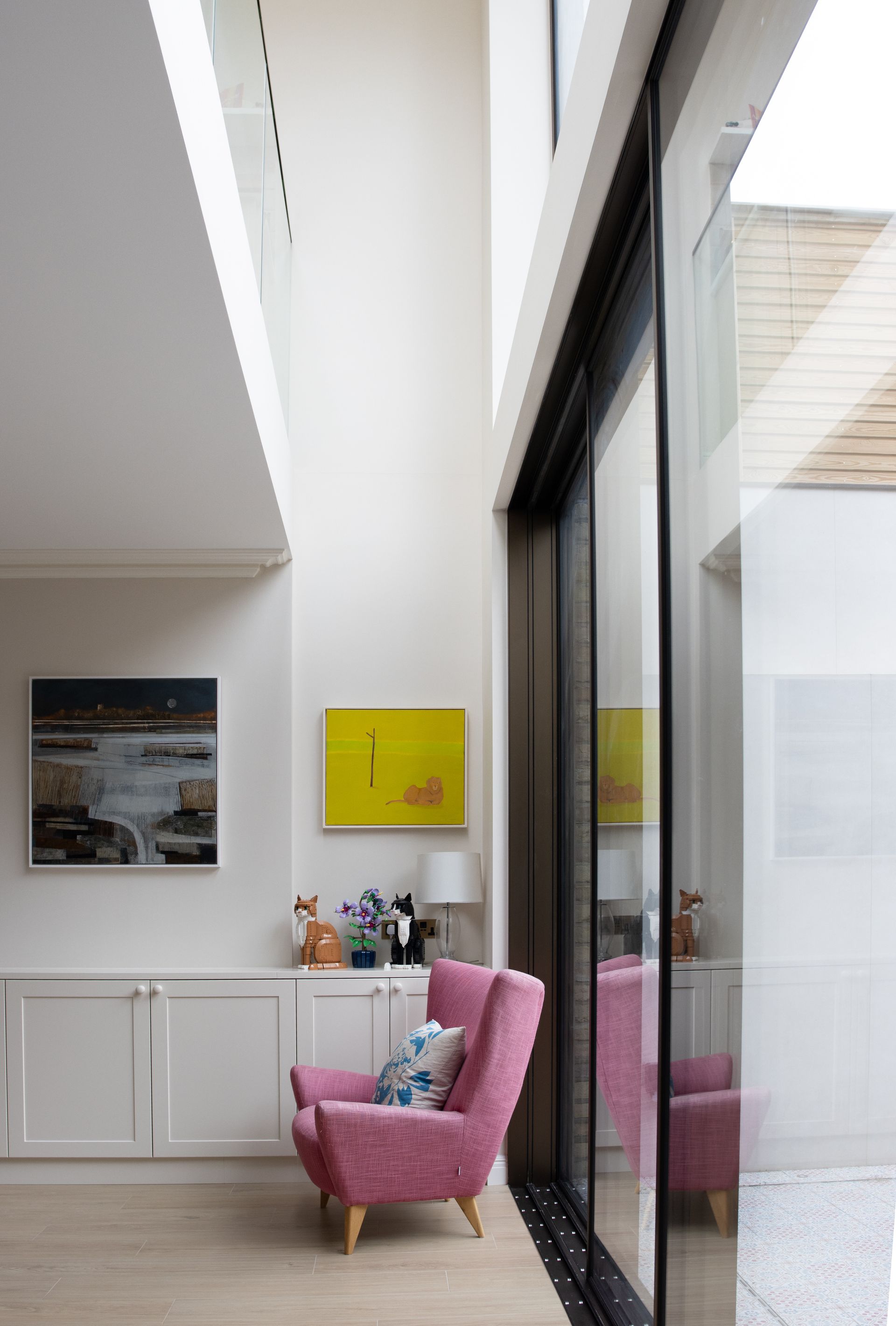 Modern staircase with black vertical railings, white walls, and a small indoor planter below.