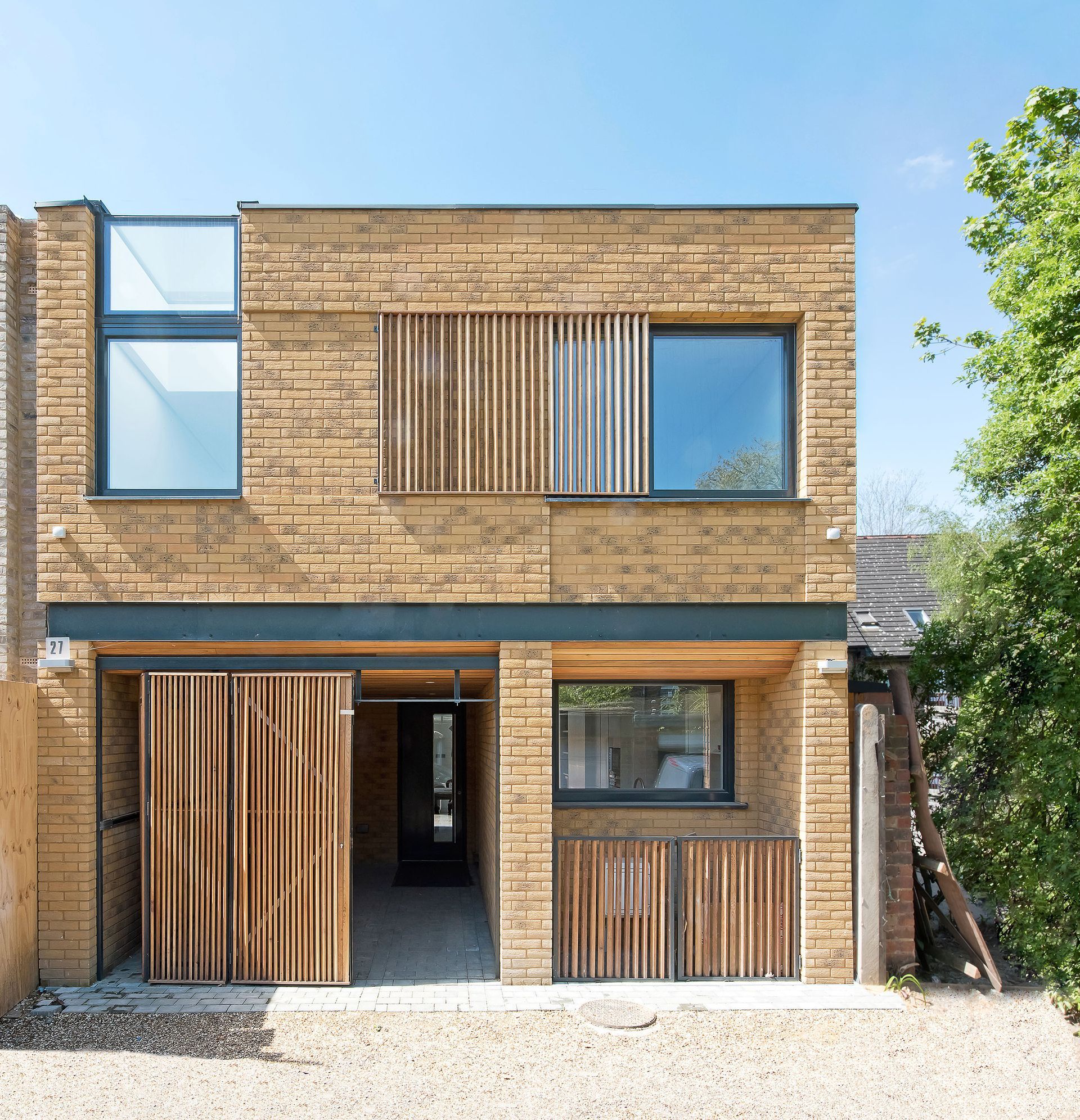 Modern two-story brick house with wood slat panels and large windows on a sunny day