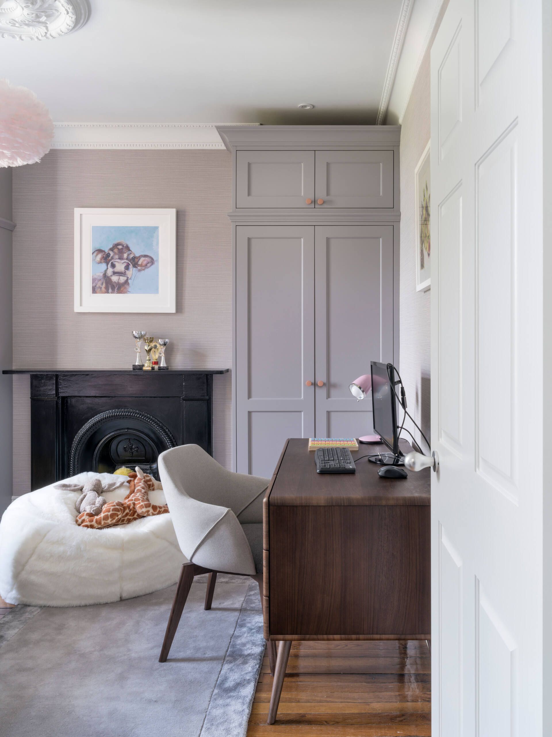 Elegant gray bedroom with a fireplace, desk, chair, and built-in wardrobe beside a white door