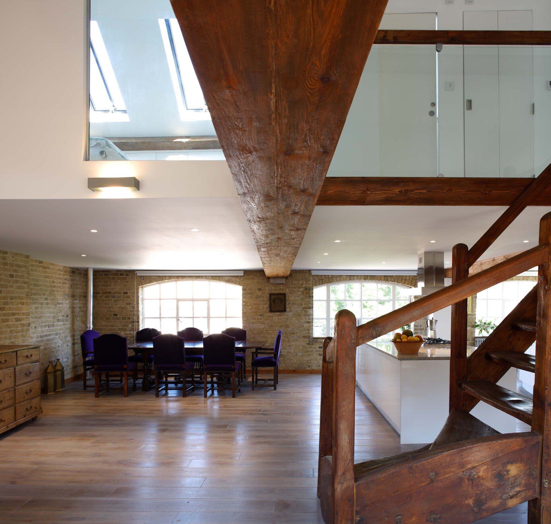 Loft-style dining room with exposed wood beams, brick walls, and a table by large windows