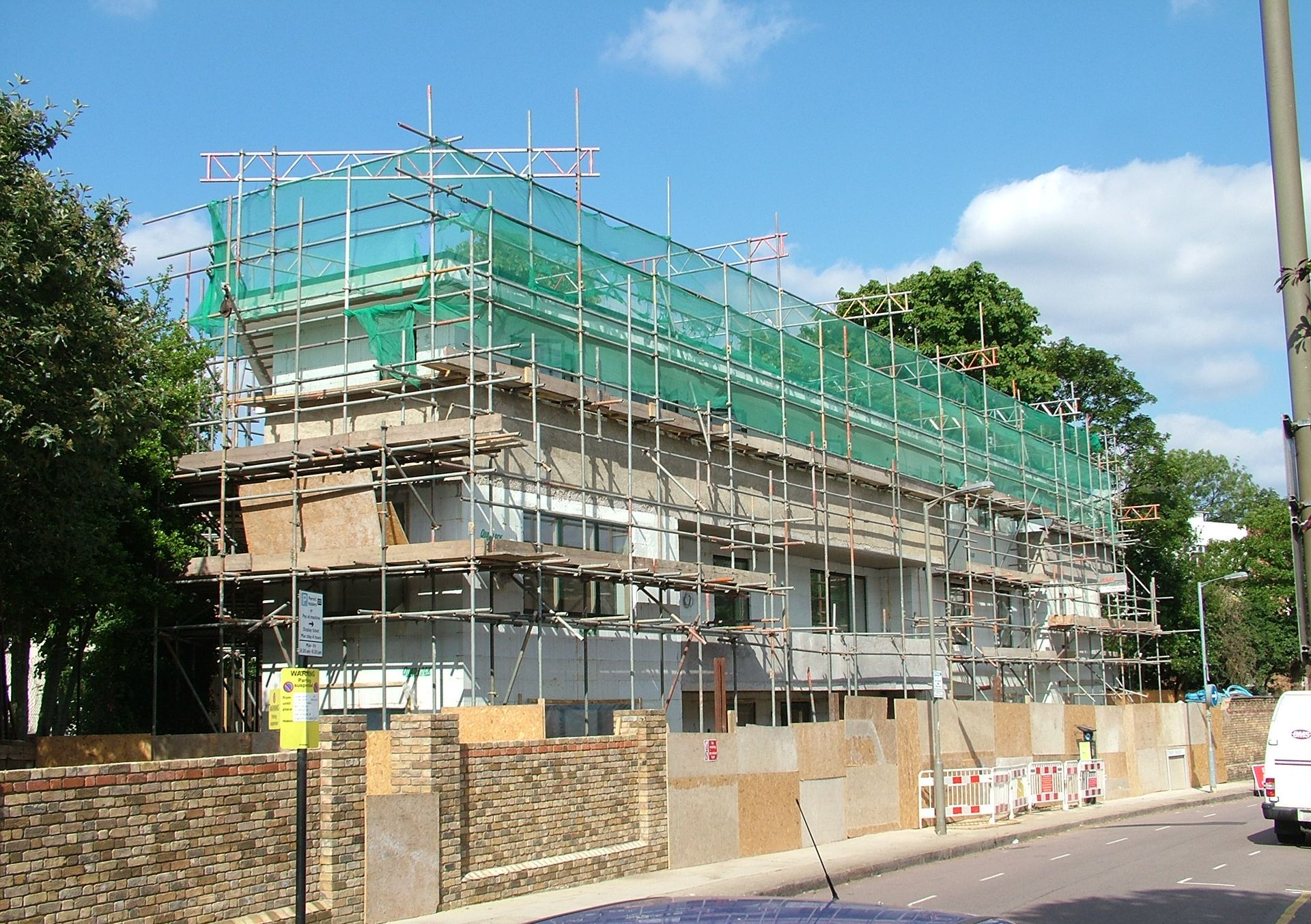 Scaffolded building under construction beside a road on a sunny day