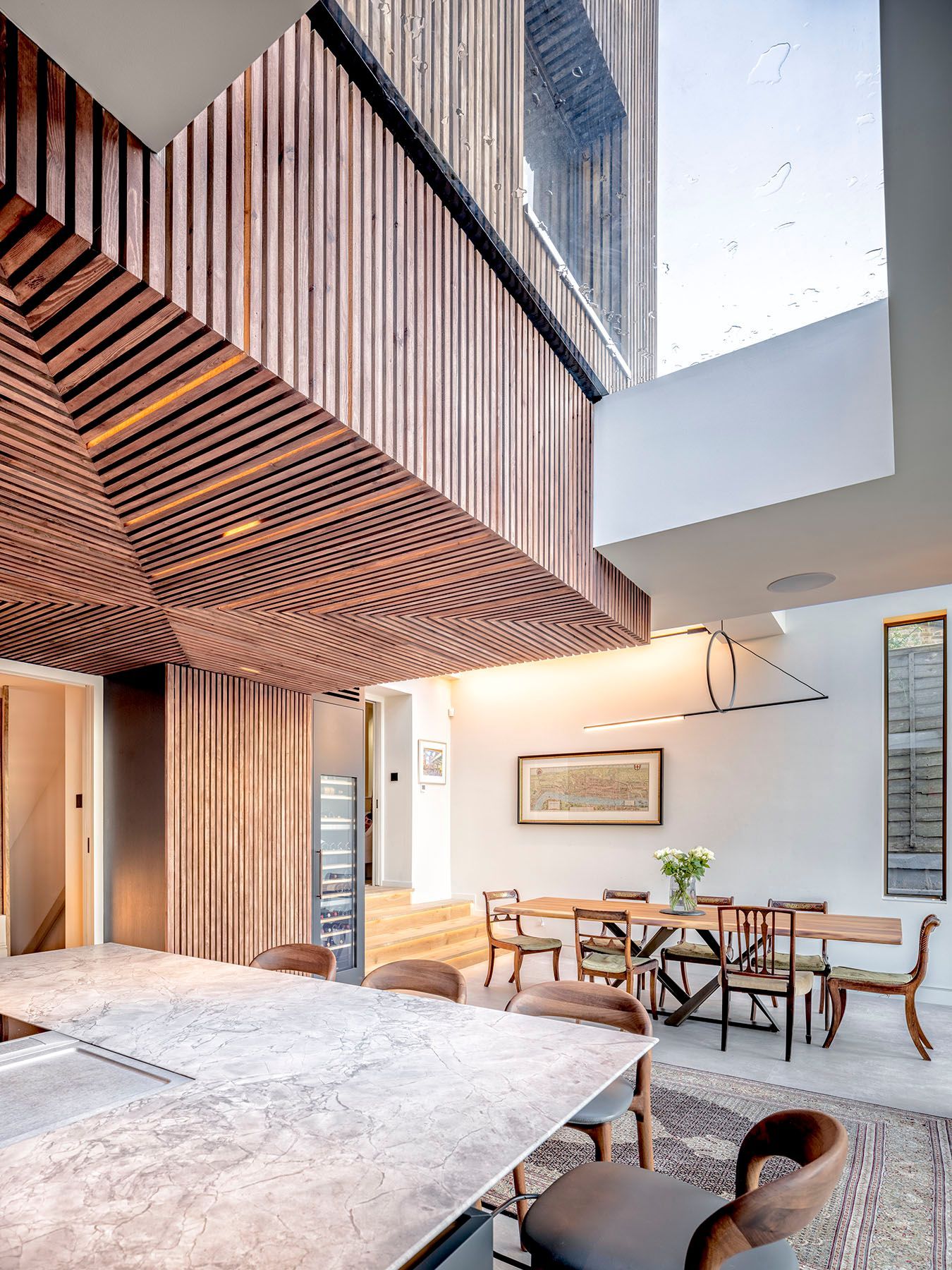 Modern courtyard patio with wood slat ceiling, concrete walls, and a dining table with chairs