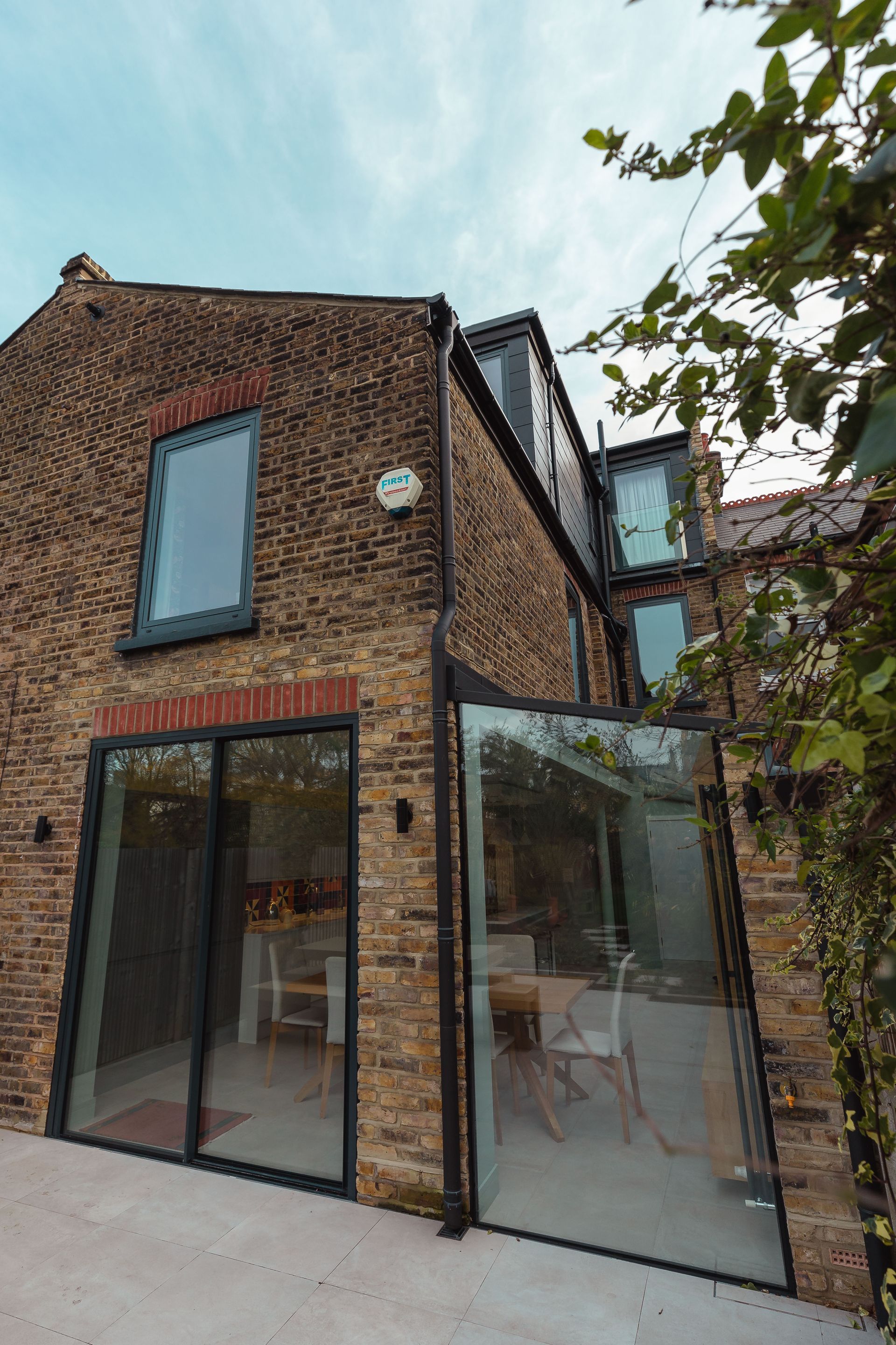 Modern brick house exterior with large glass doors and windows under a cloudy sky