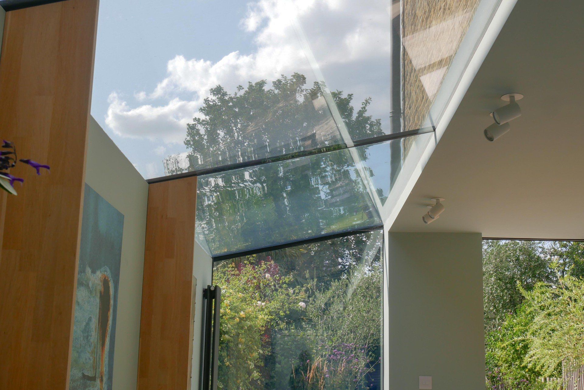 Modern home interior with glass walls and ceiling opening to trees and sky
