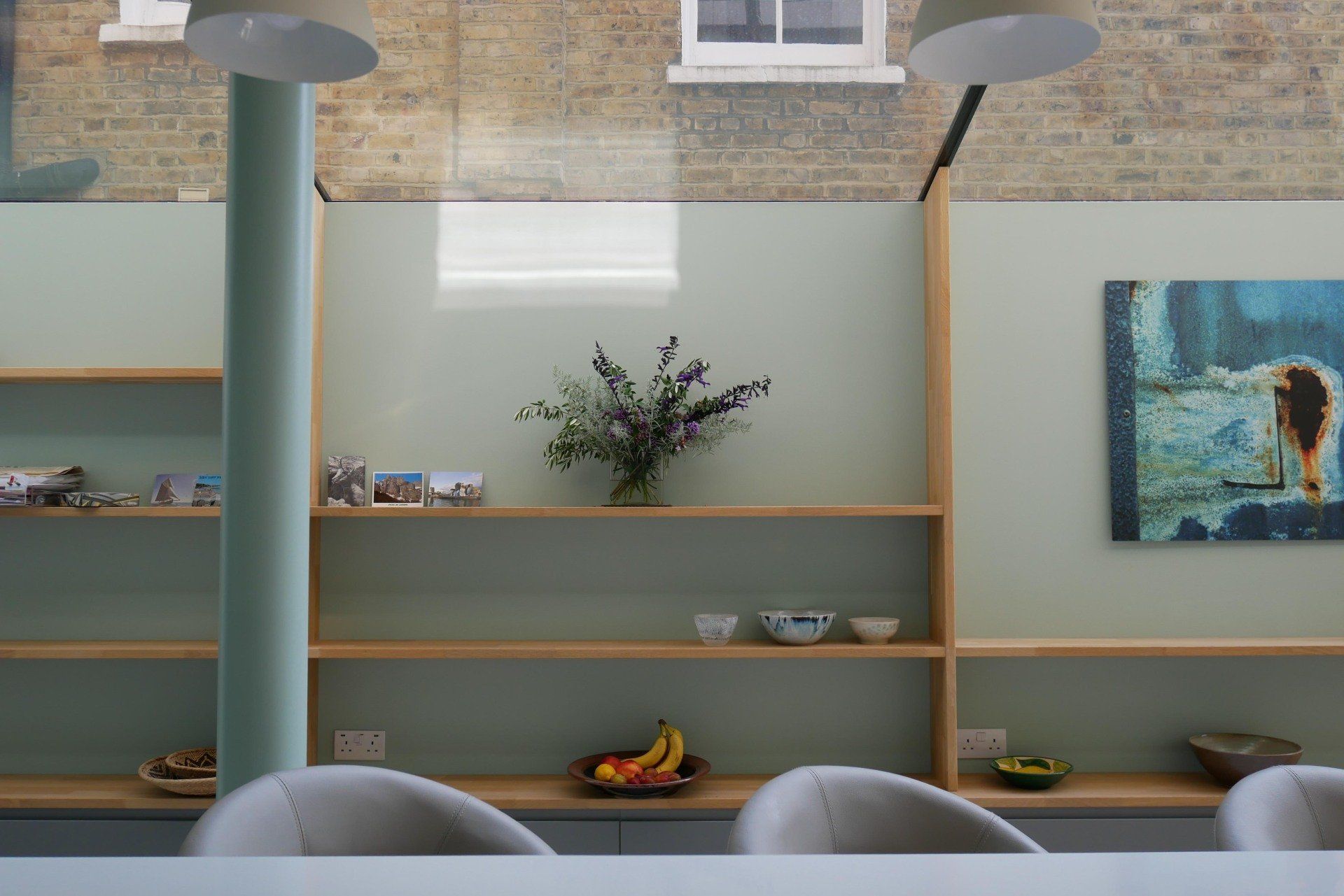 Modern cafe interior with shelves, pendant lights, bowls, flowers, and a mural on the wall